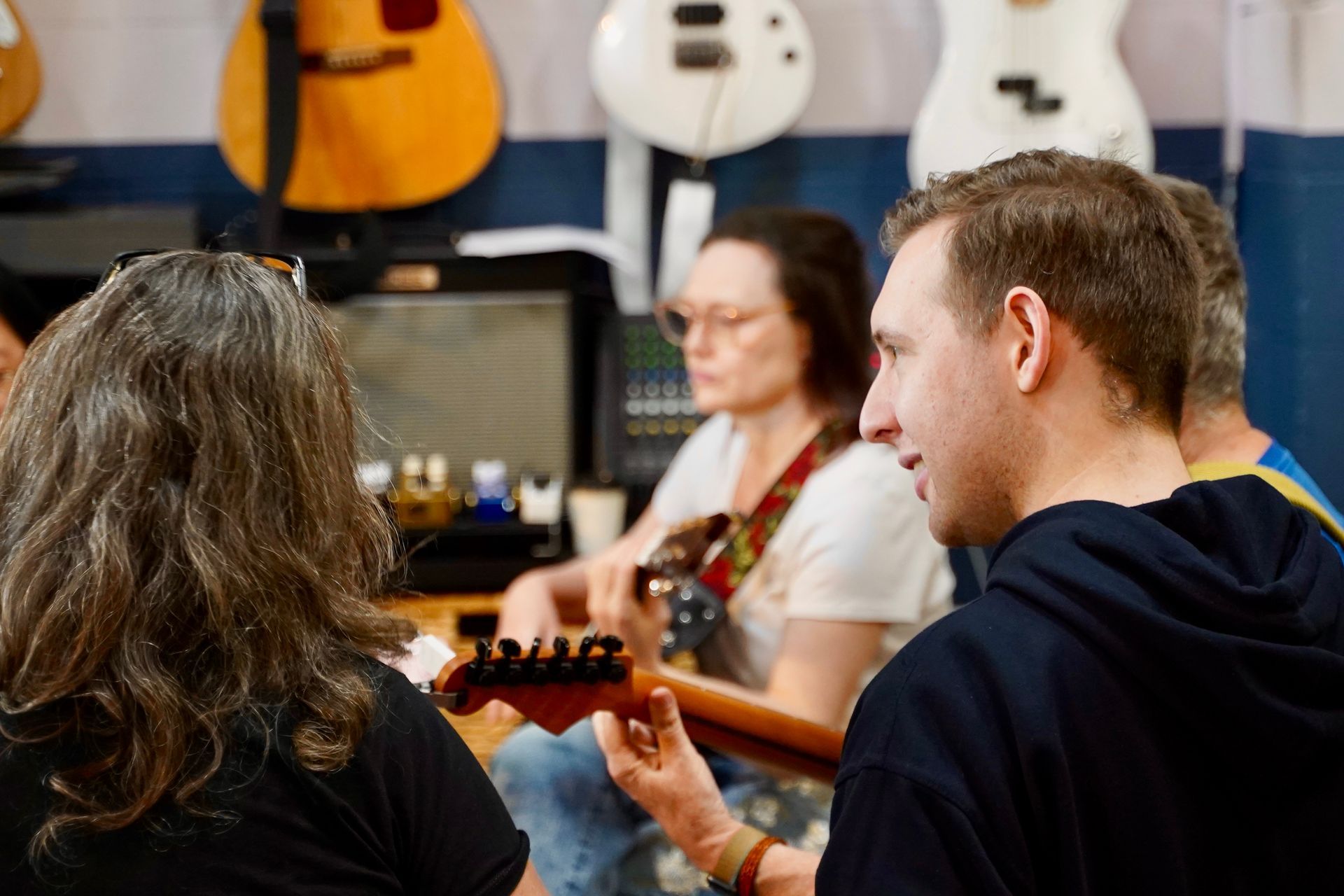 A guitar teacher talking to a group of students in a lesson