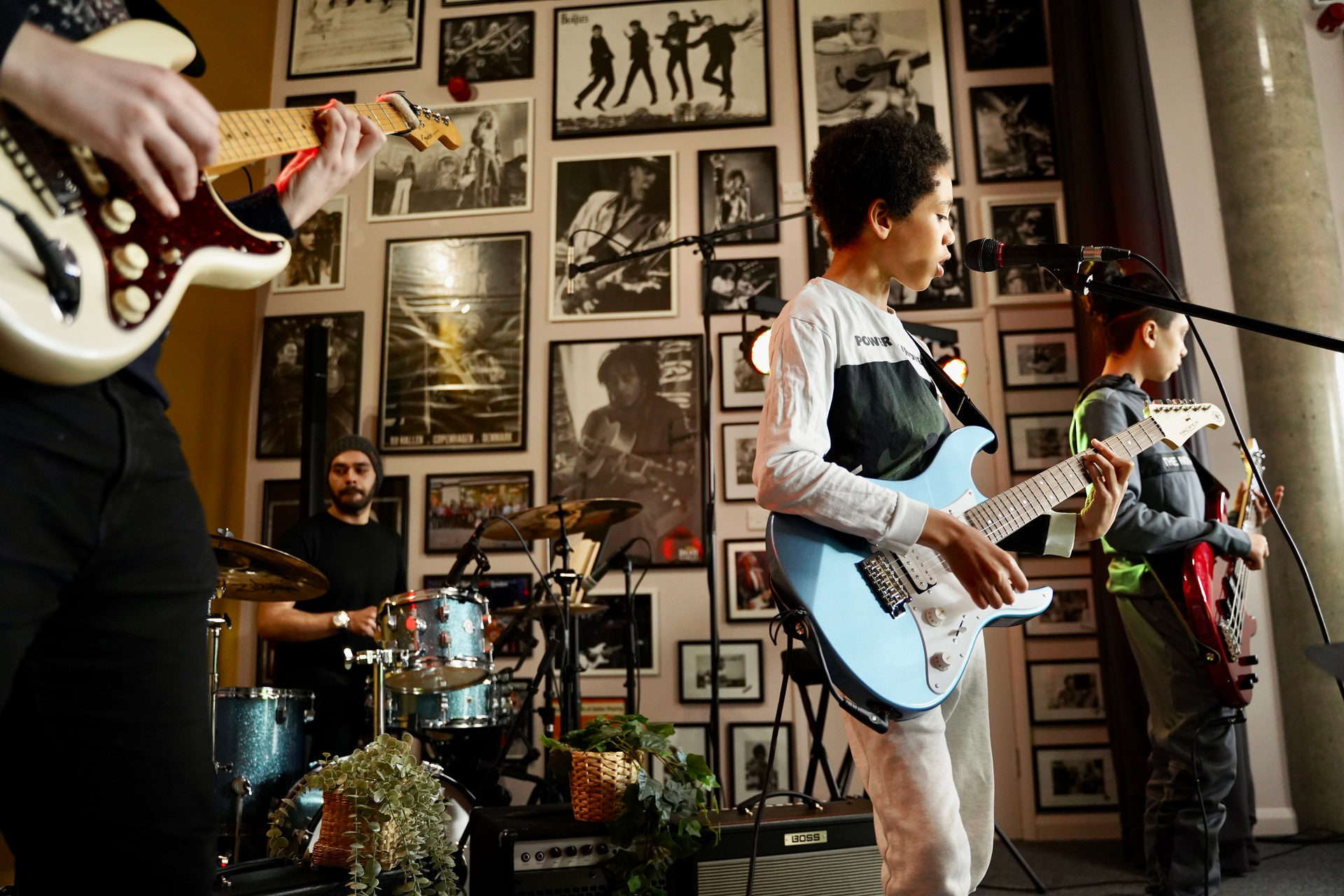A group of teenagers are playing guitars and singing in a band at Guitar Tuition East London.