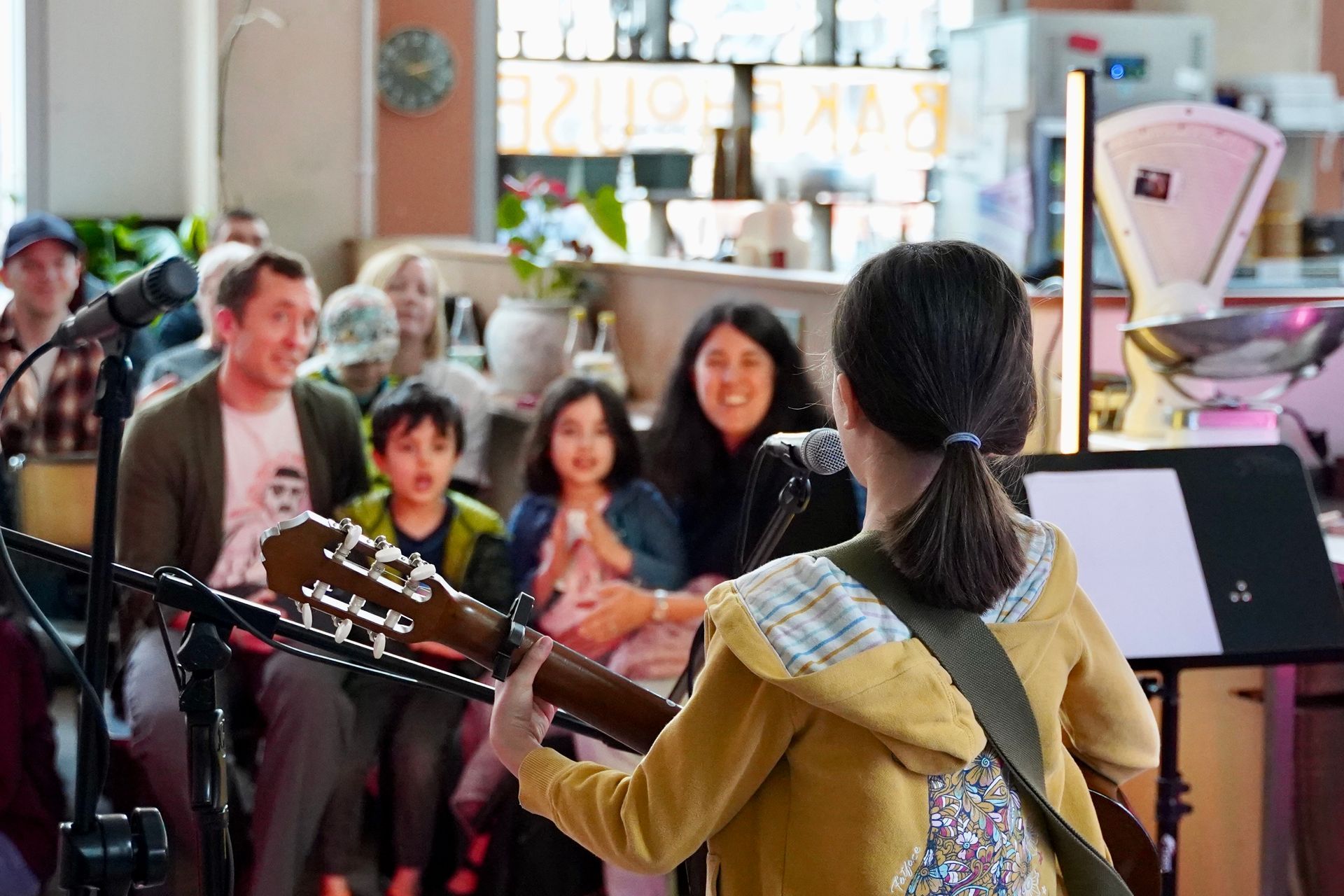 A woman is playing a guitar in front of a crowd of people.