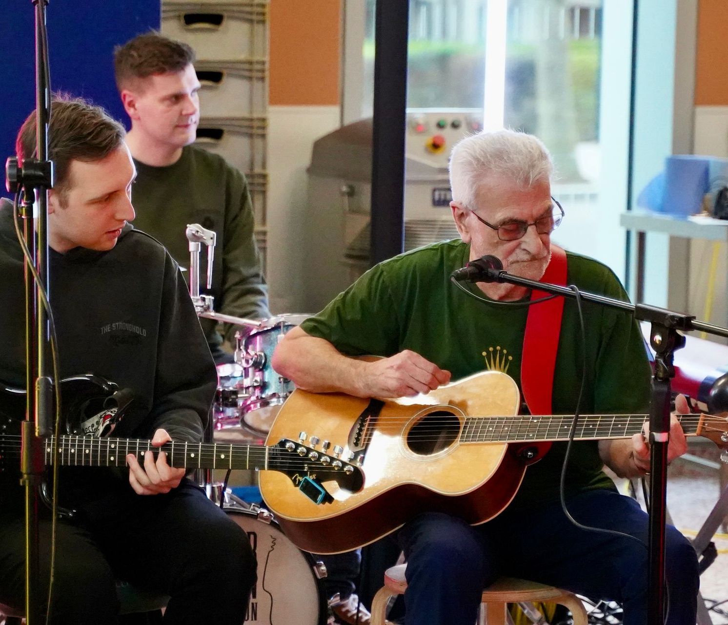 A man playing an acoustic guitar in front of a microphone