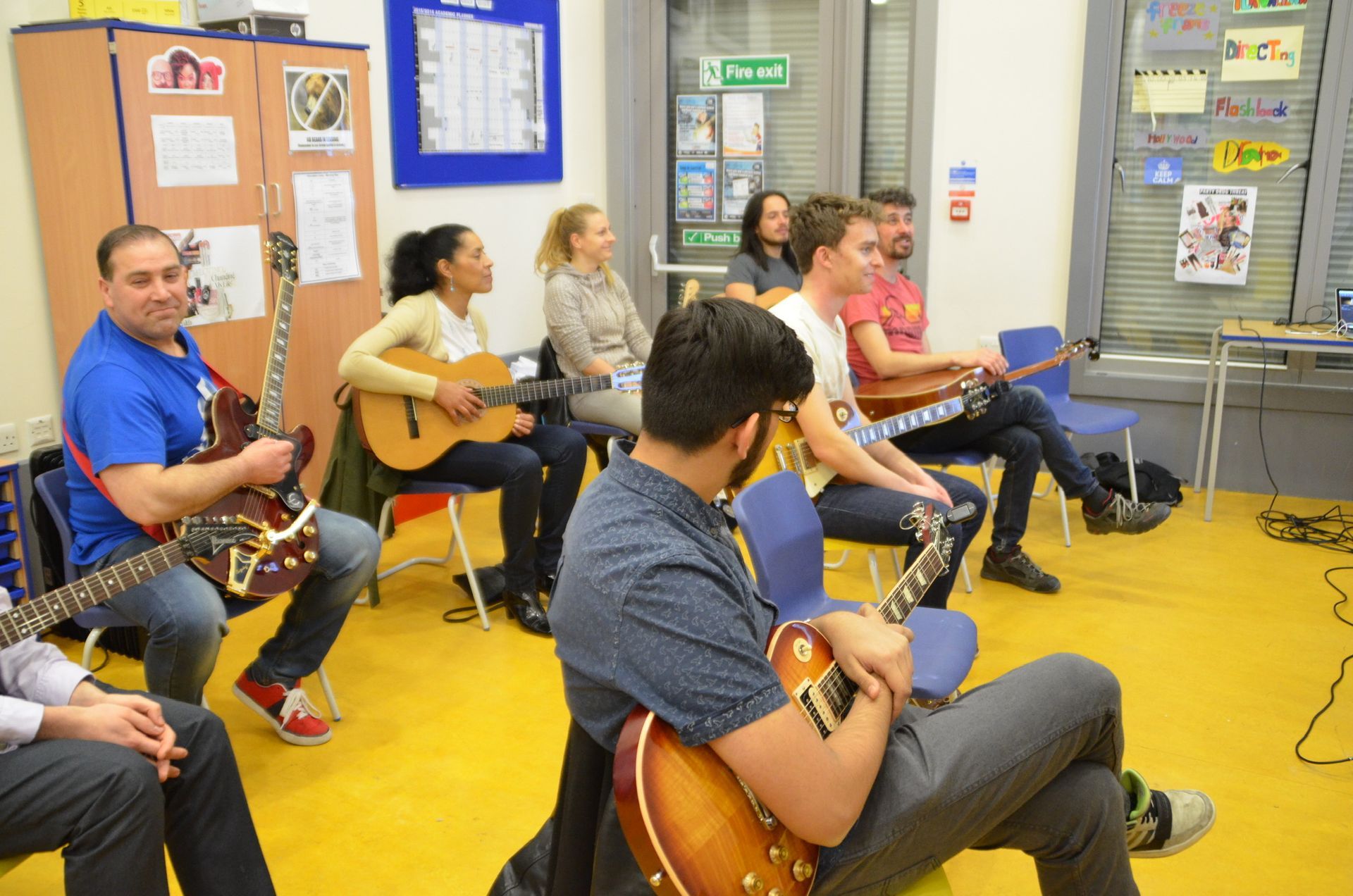 A group of people are sitting in chairs playing guitars.