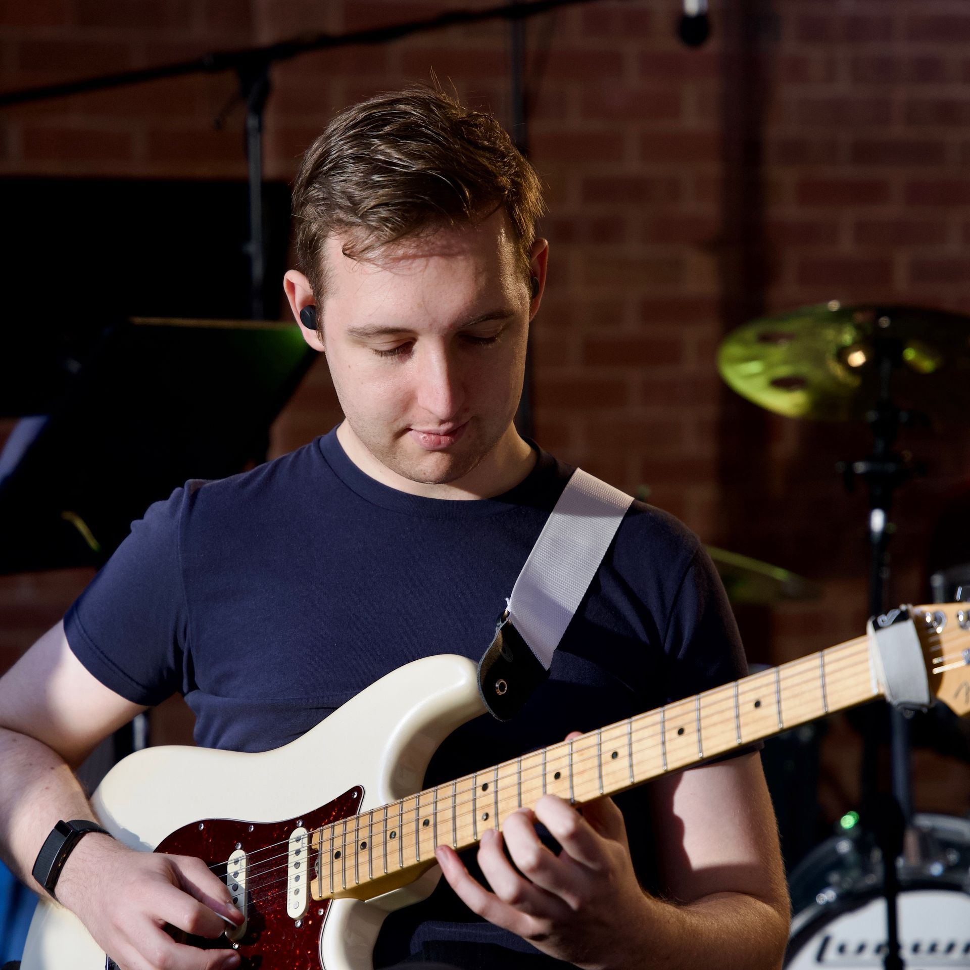 A man in a blue shirt is playing an electric guitar
