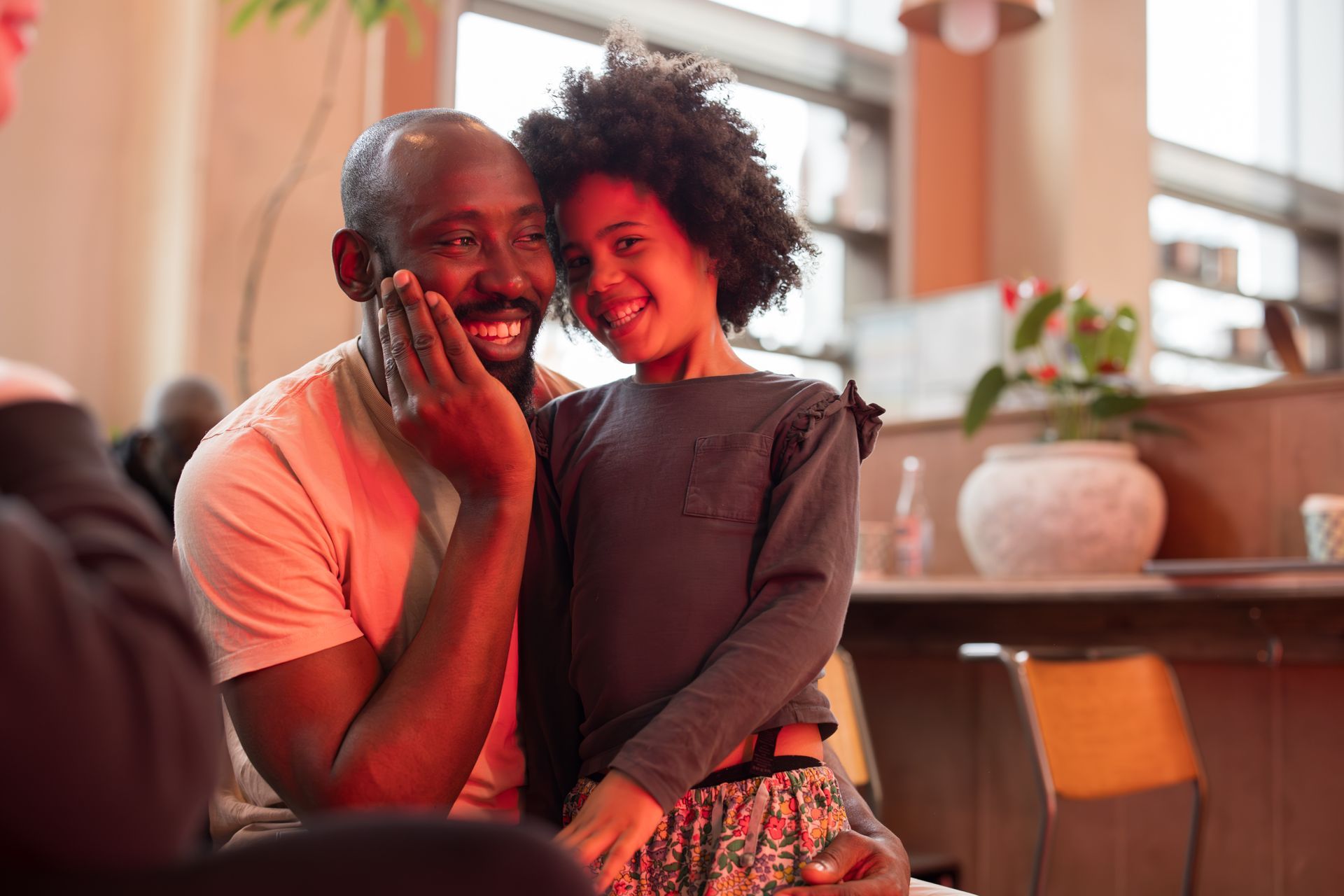 A man and a little girl are sitting next to each other and smiling.