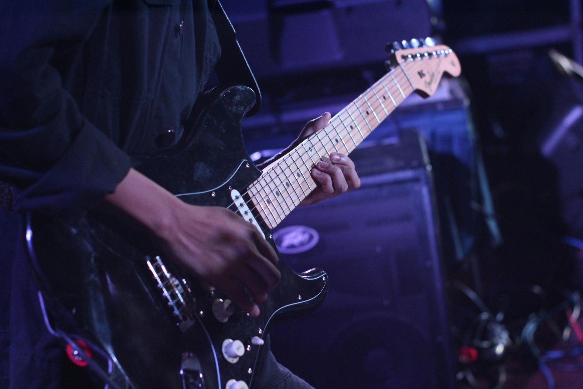A man is playing an electric guitar in a dark room