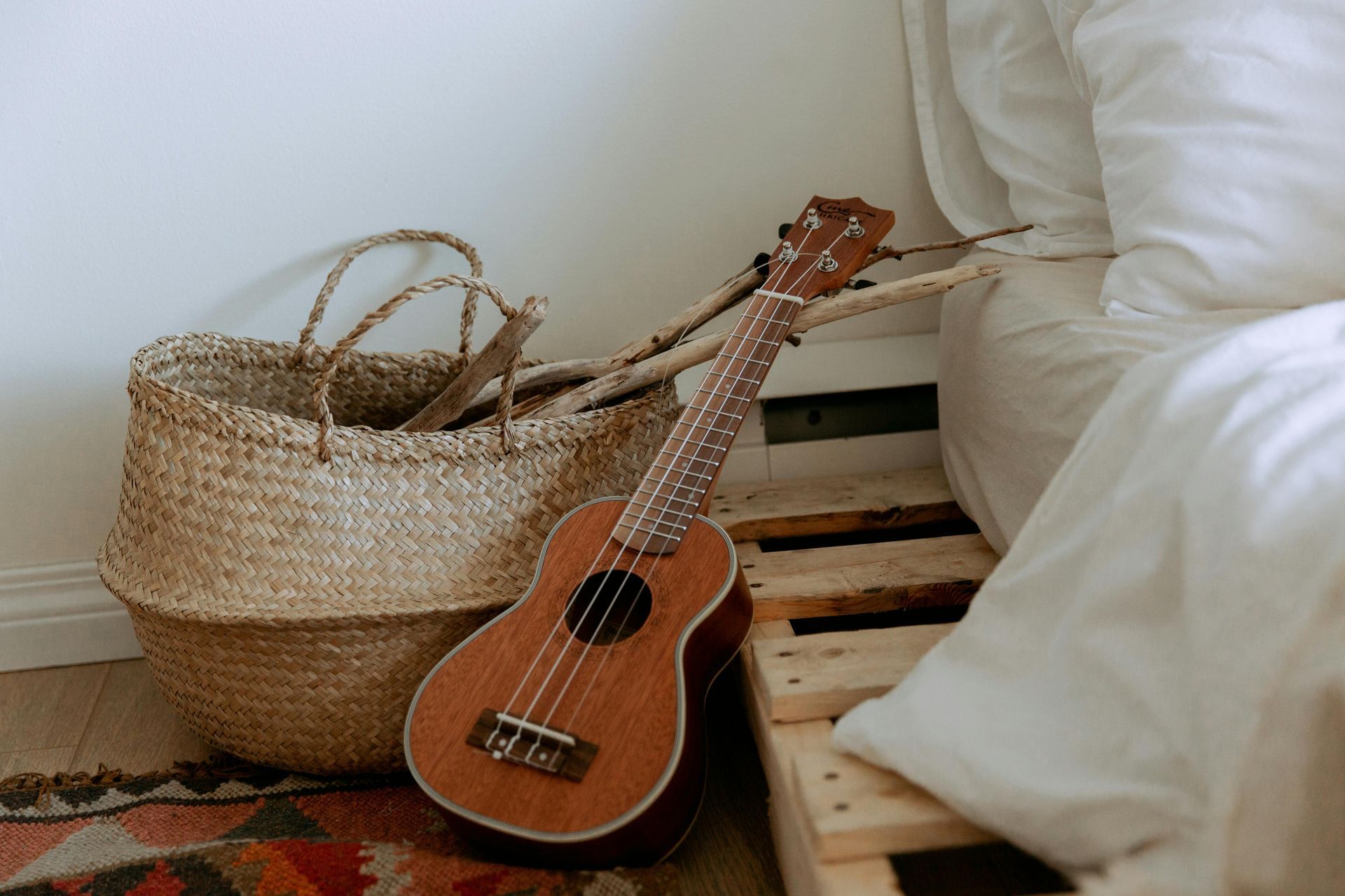 A guitar is sitting on a wooden pallet next to a basket.