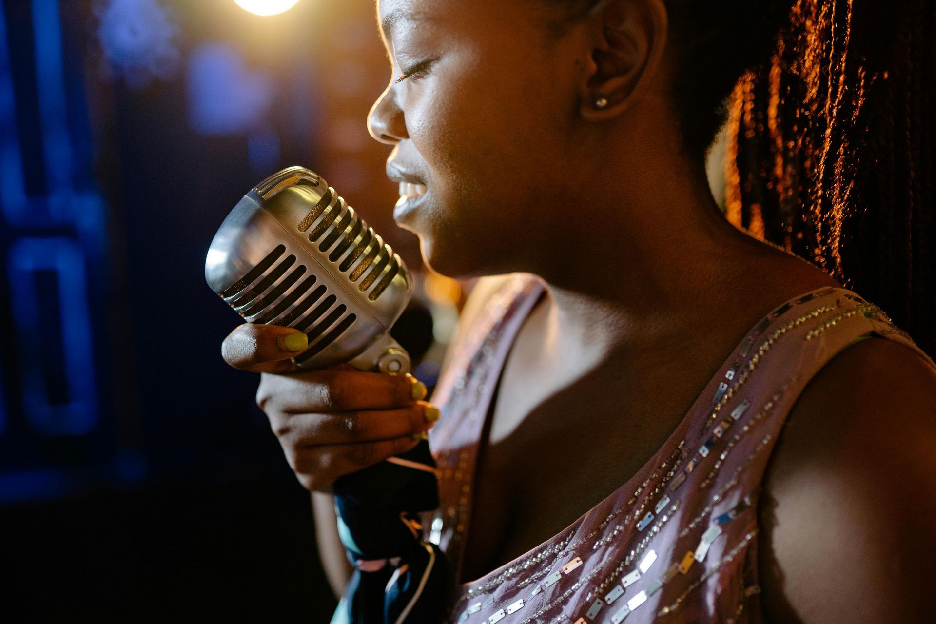 A woman is singing into a microphone in a dark room.