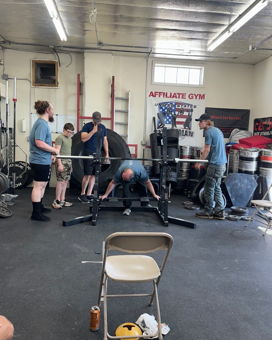 Weightlifter prepping for a lift at a gym, with spotters present.