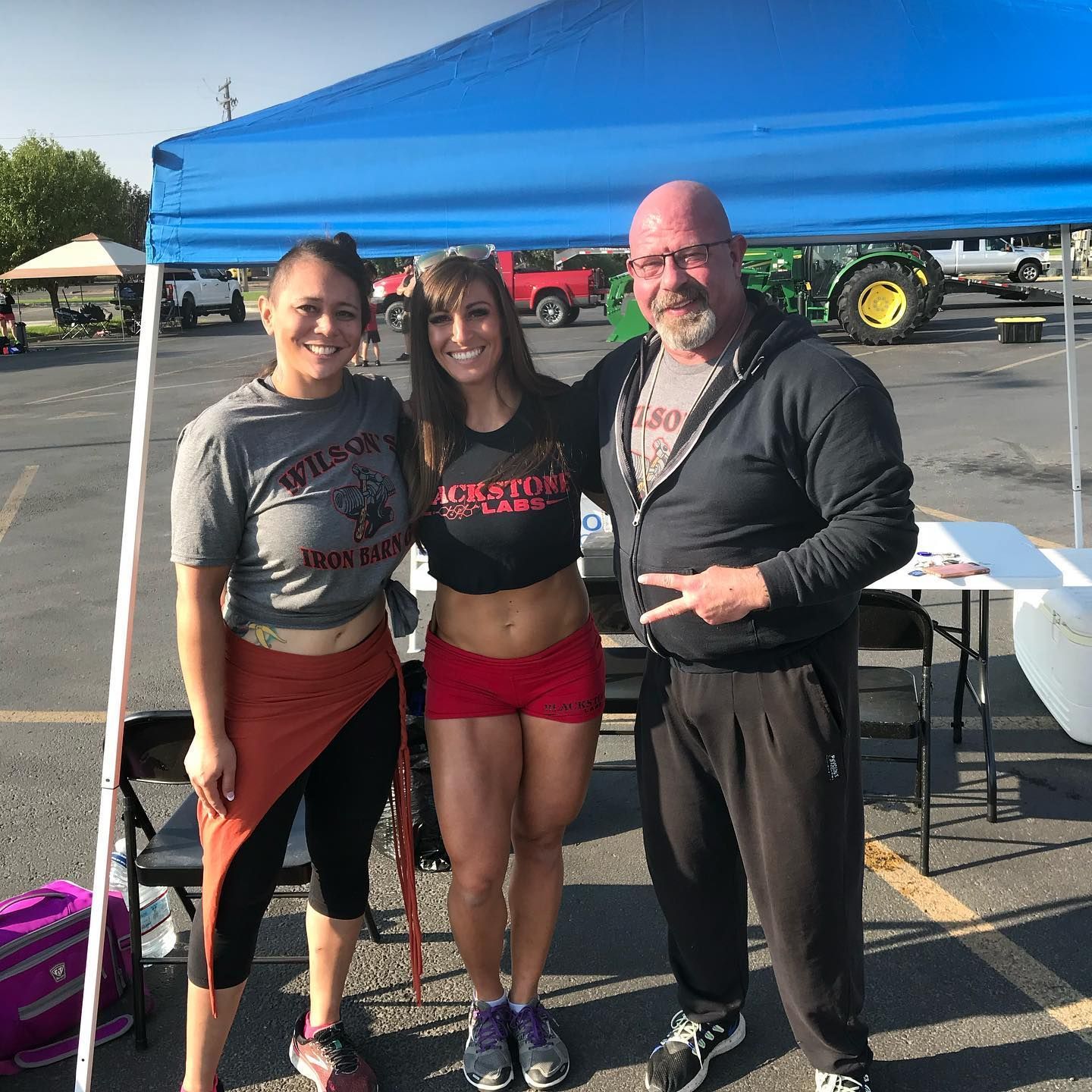Three people posing under a blue canopy outside. 