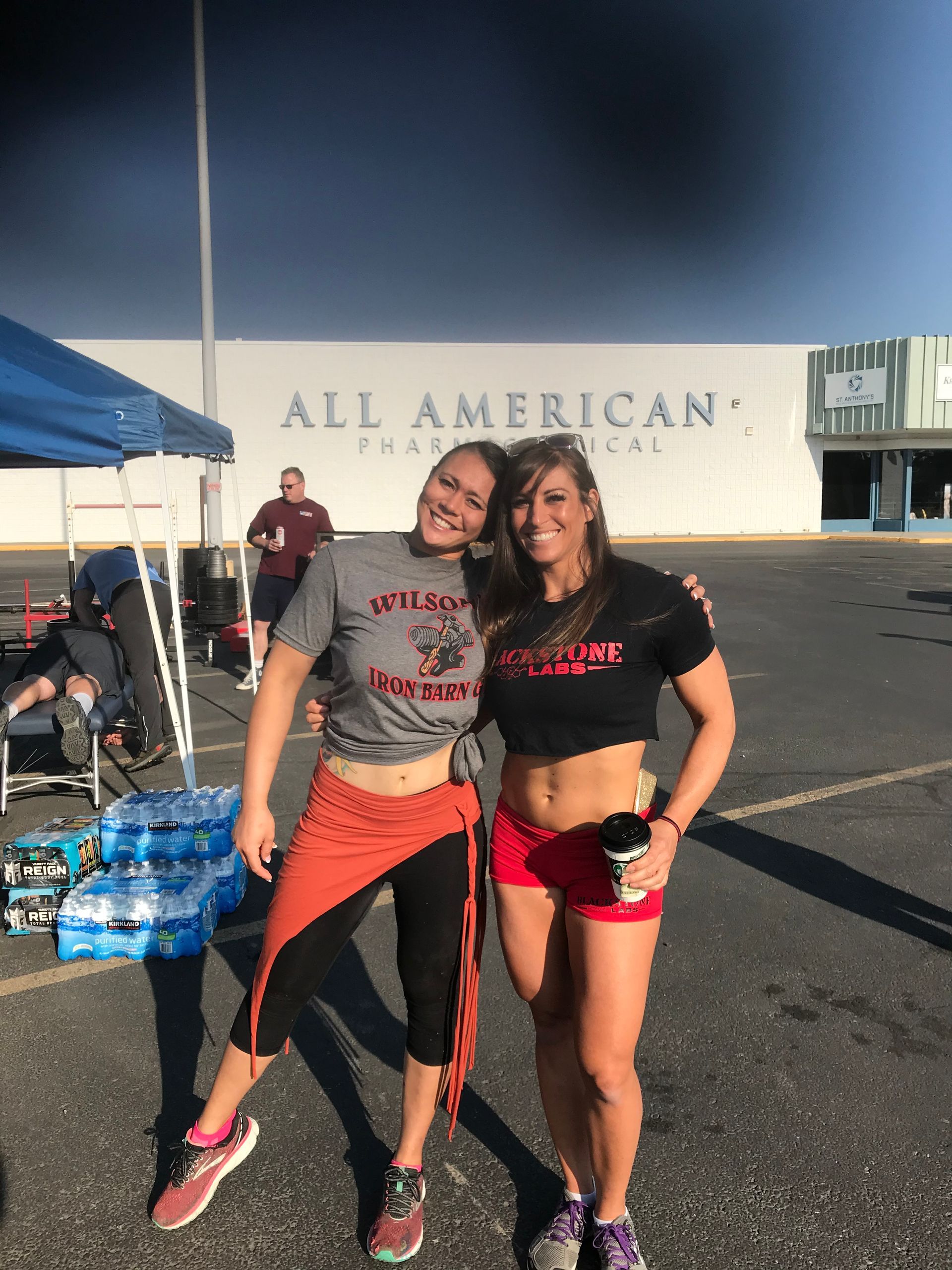 Two women pose in front of a building that reads