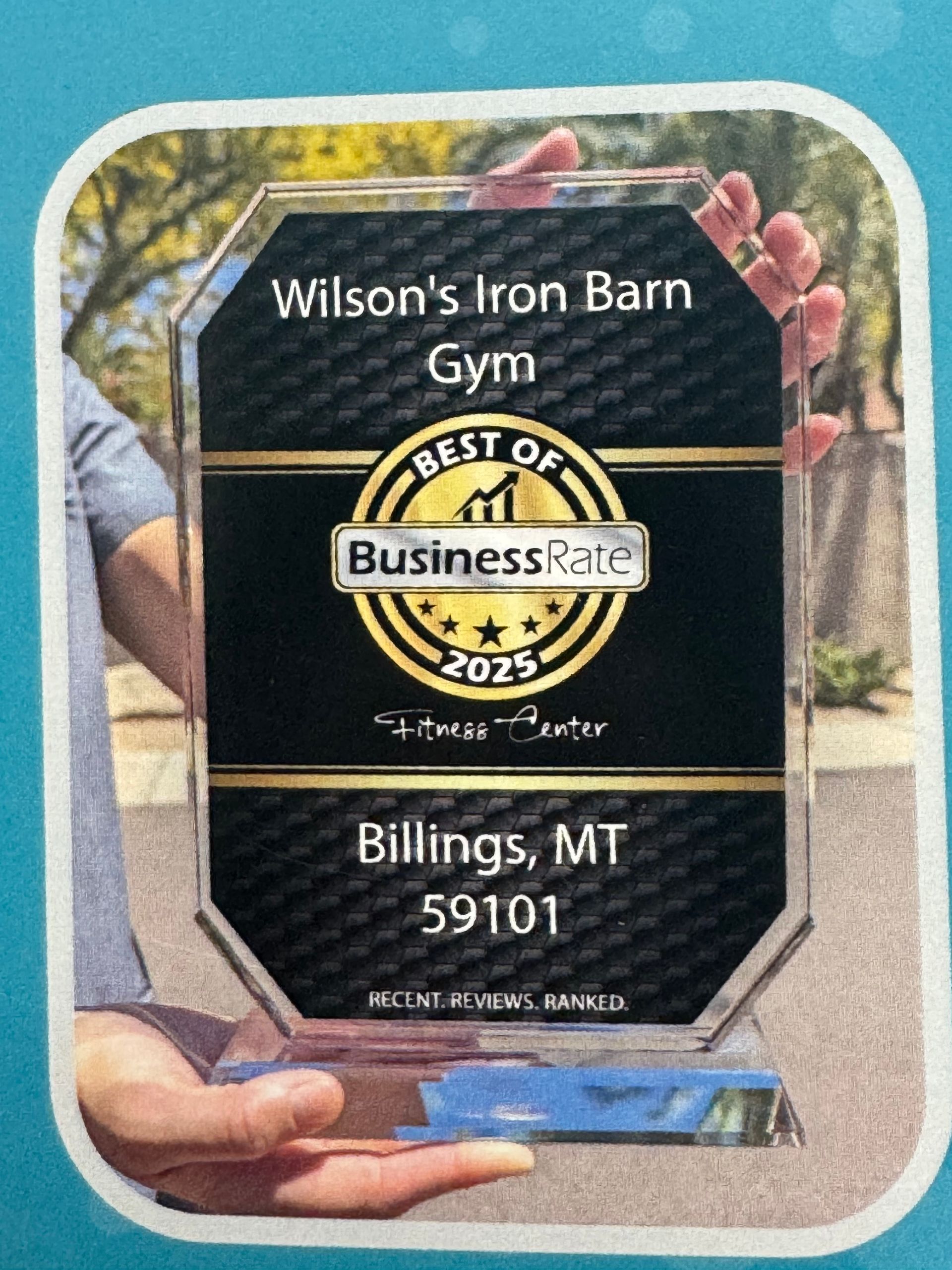 Person holding an award for Wilson's Iron Barn Gym,