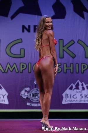 Woman in red bikini, posing on stage at Big Sky Championship competition.