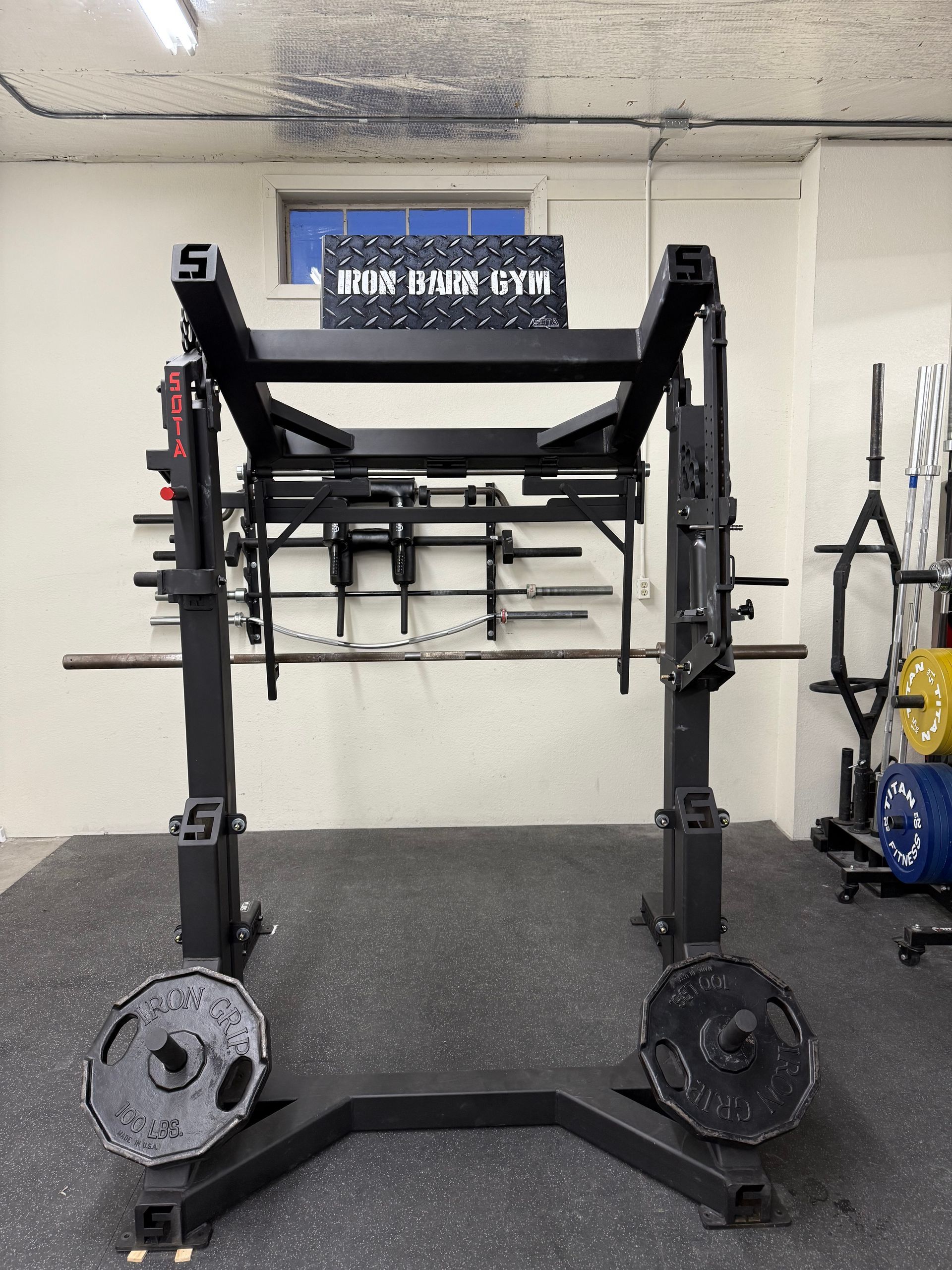 Black weightlifting power rack with weights and bars in a gym setting.