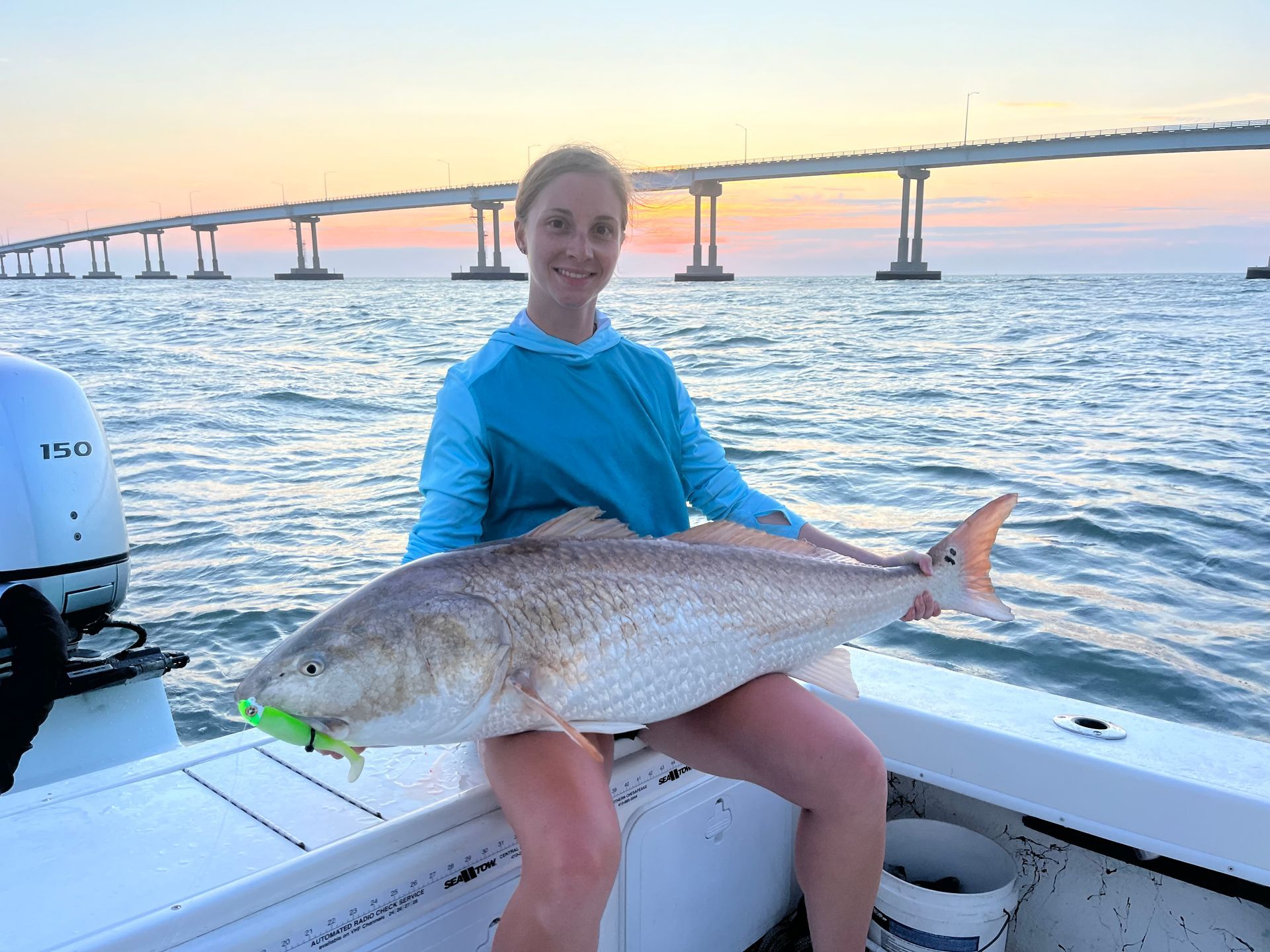 A woman is sitting on a boat holding a large fish.