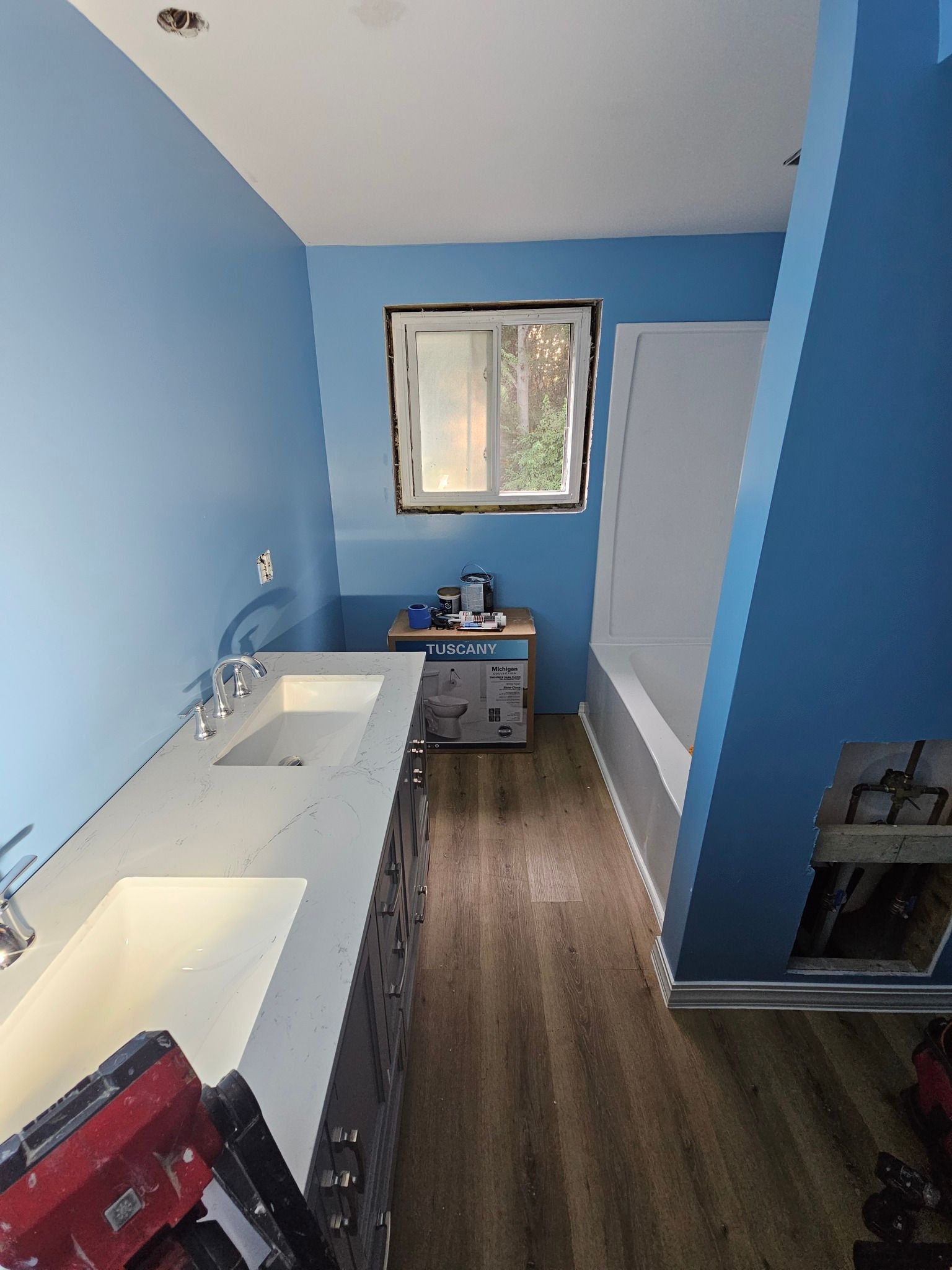 Bathroom with blue walls, double sink vanity, window, and bathtub.