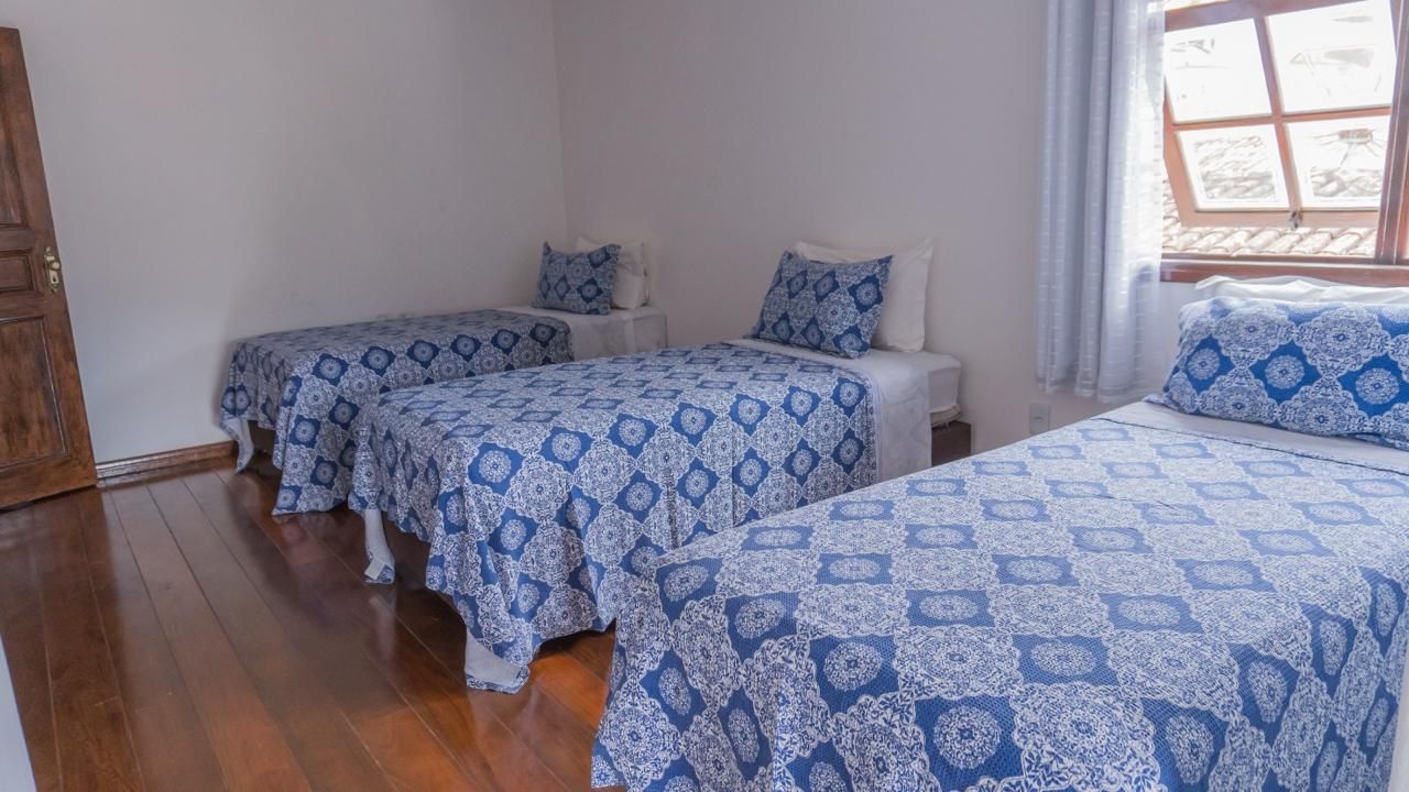 Um quarto com três camas e uma janela.