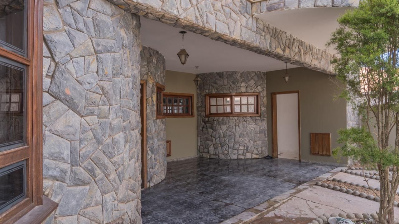 Uma casa com um muro de pedra e uma árvore na frente.