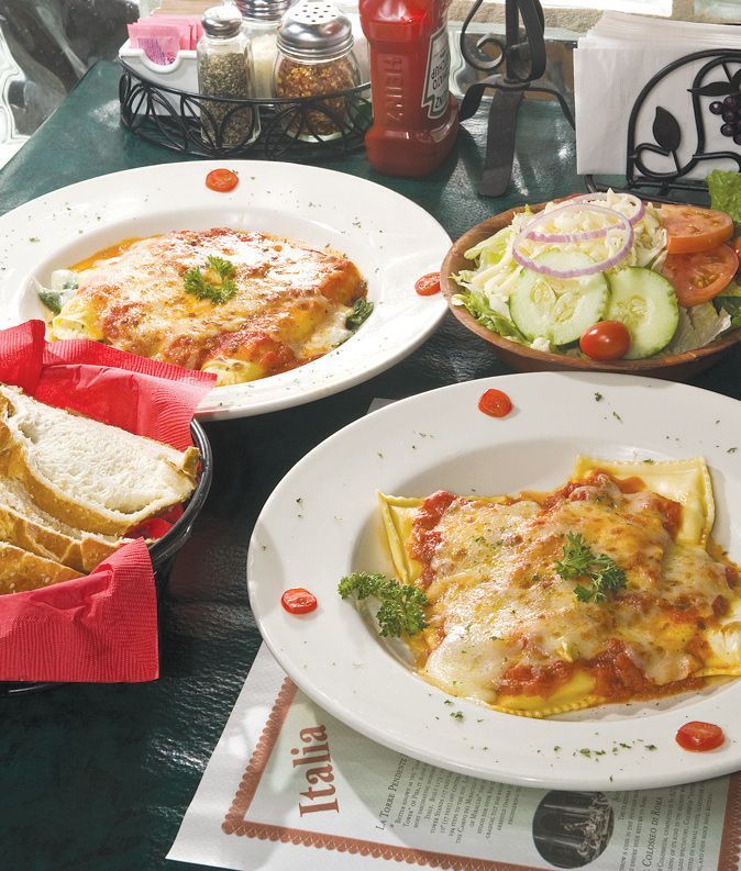 Italian dishes on a table: pasta, salad, and bread.