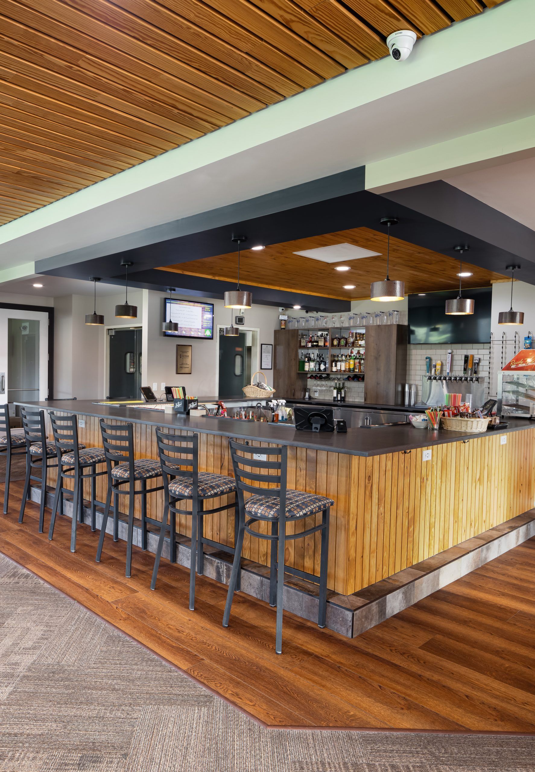 A restaurant with a long wooden bar and chairs.