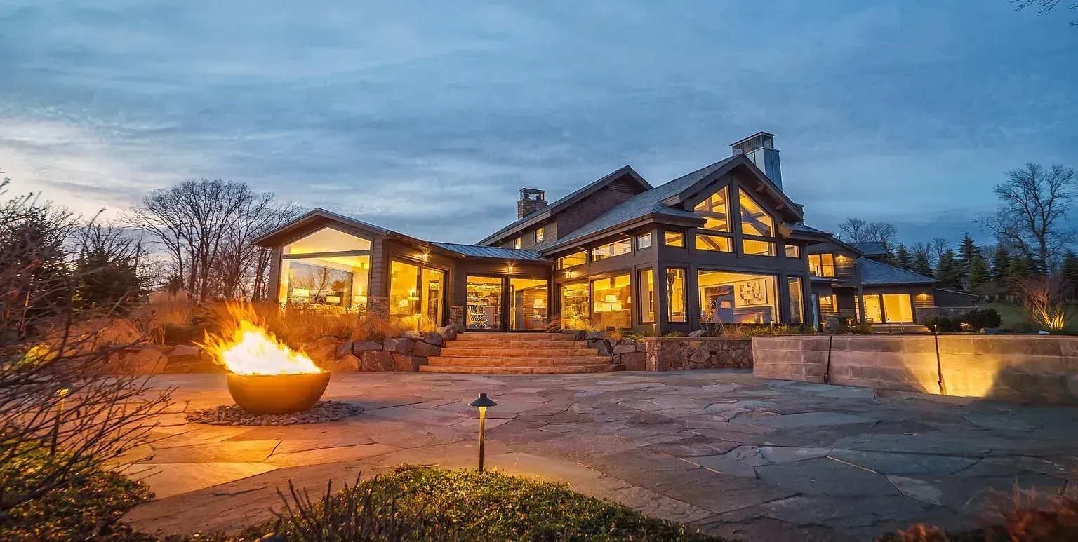 A large house with a fire pit in front of it at night.