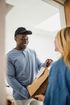 A man is delivering a package to a woman in a doorway.