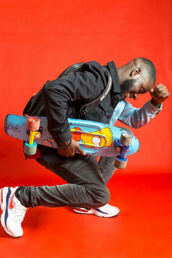 A man is kneeling down while holding a skateboard.