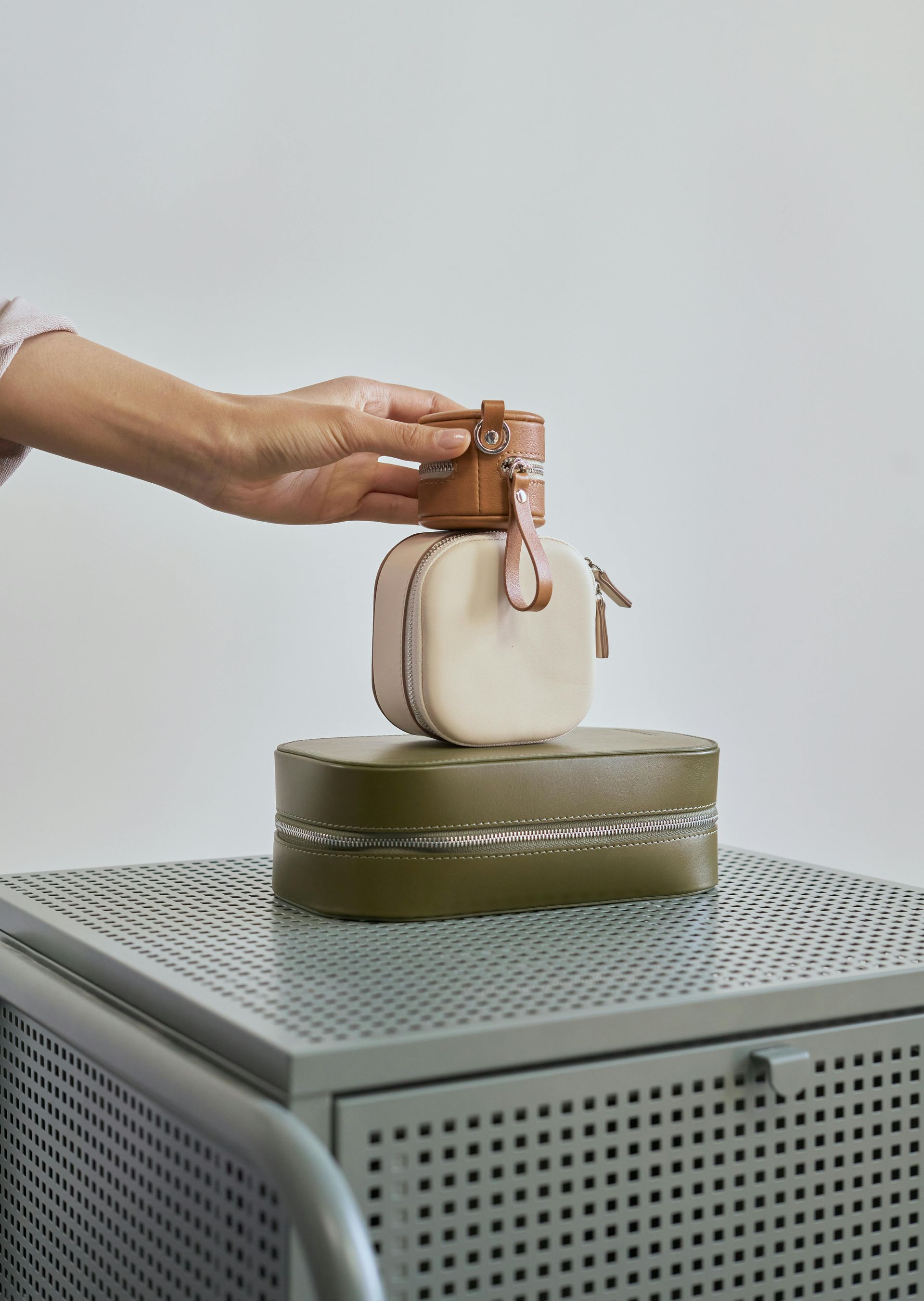 A person is holding a small white bag on top of a green box.