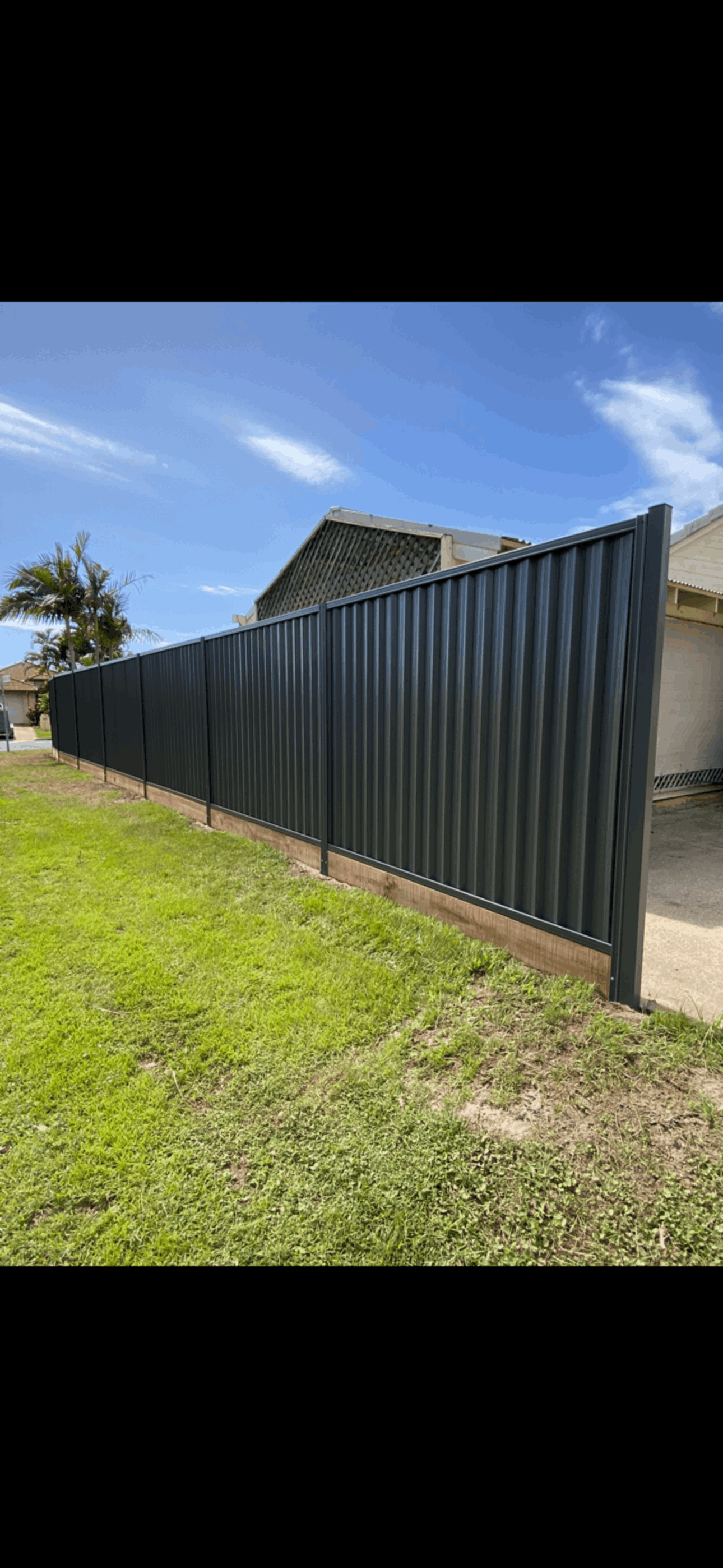 A fence is surrounded by grass and trees in a yard.