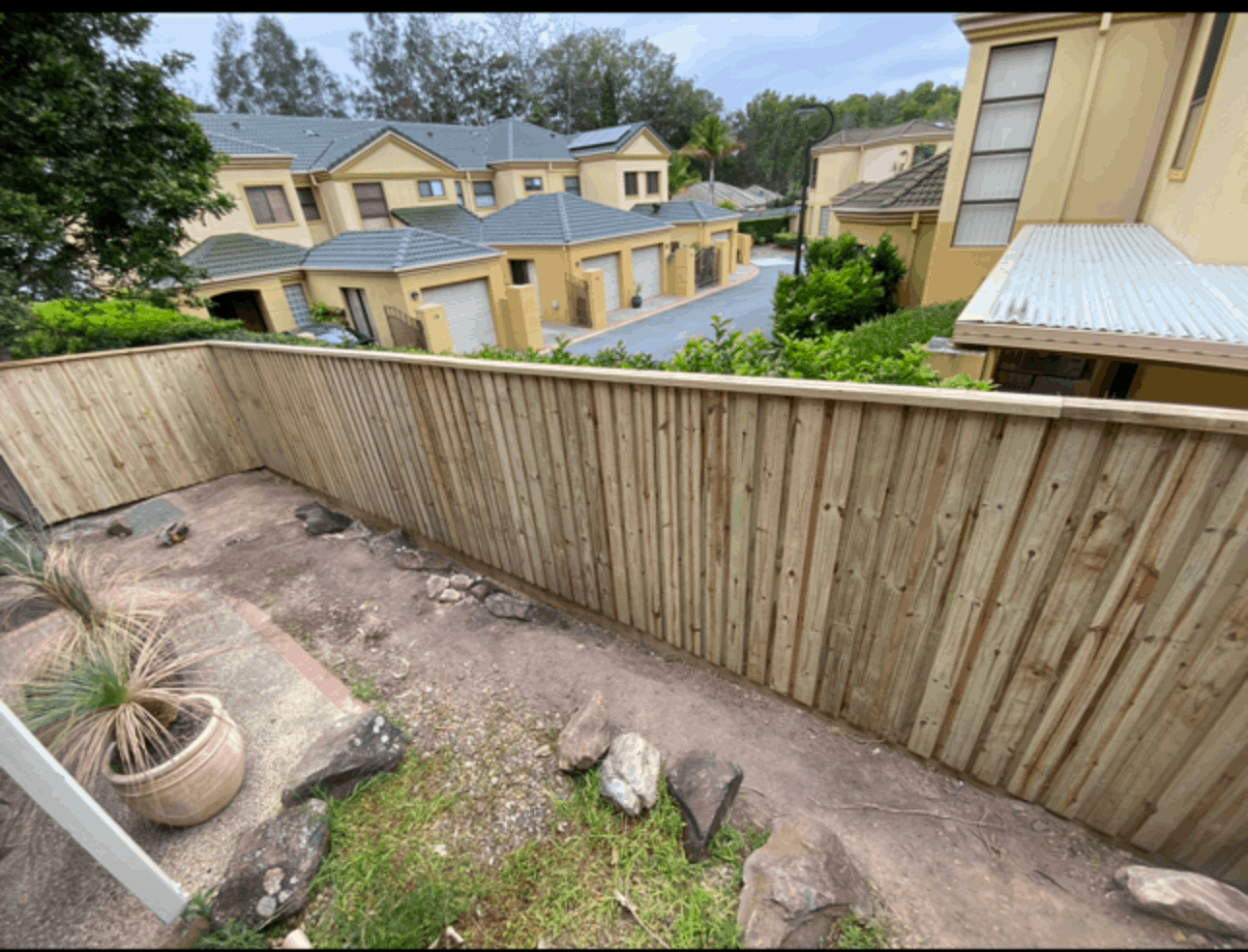 A wooden fence is surrounded by houses in a residential area.