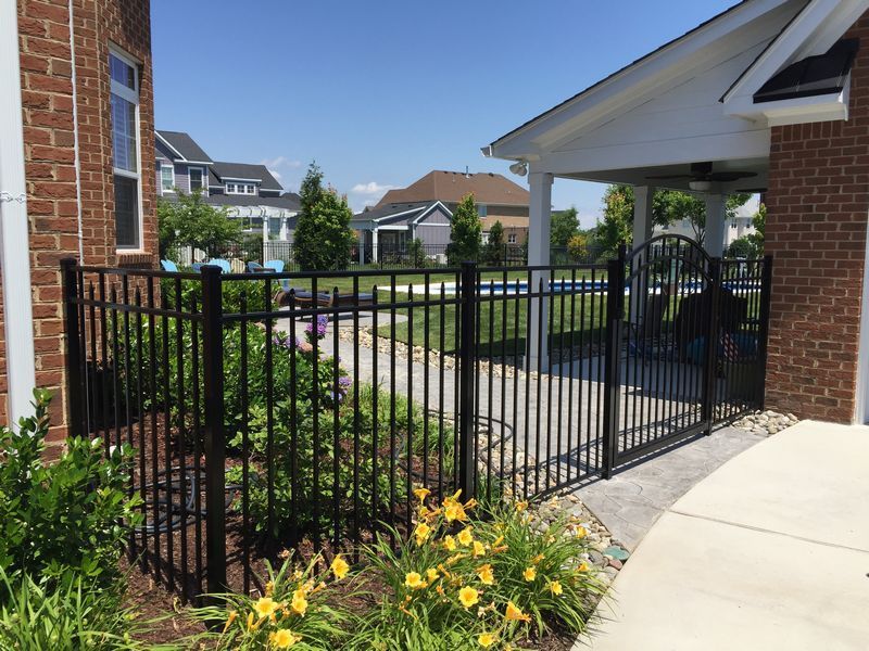 A brick house with a black fence surrounding it