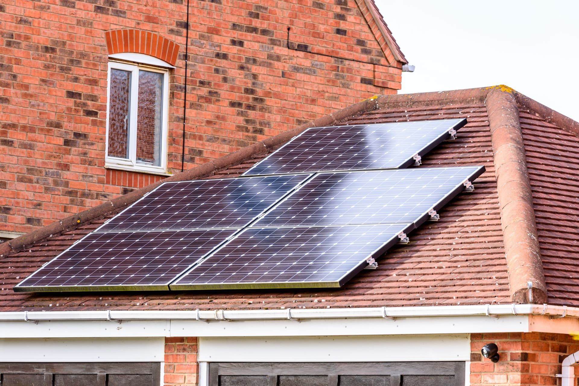 There are two solar panels on the roof of a brick house.