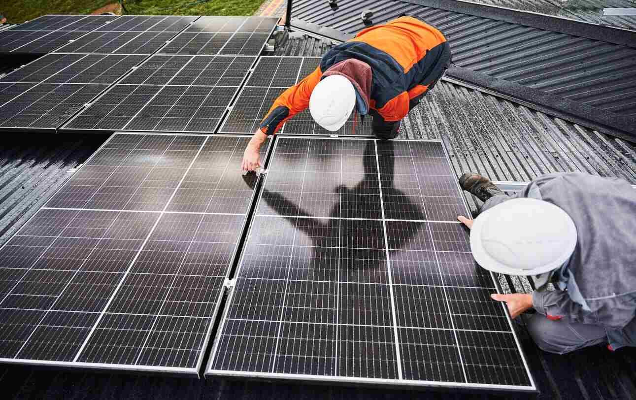 Two men are installing solar panels on a roof.