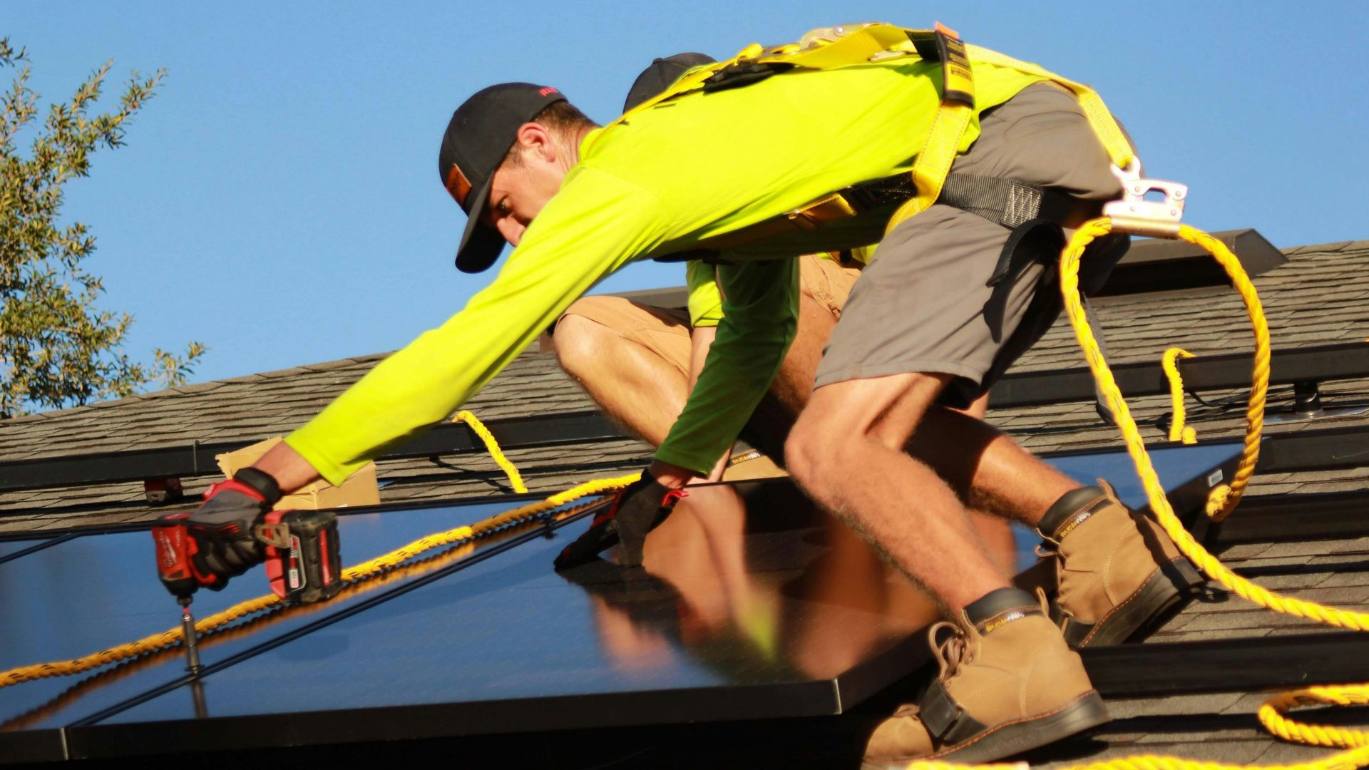 A man is installing solar panels on the roof of a house.