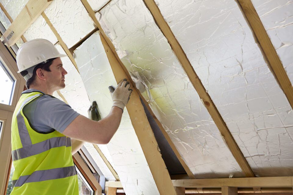 A man is installing insulation on the roof of a building.
