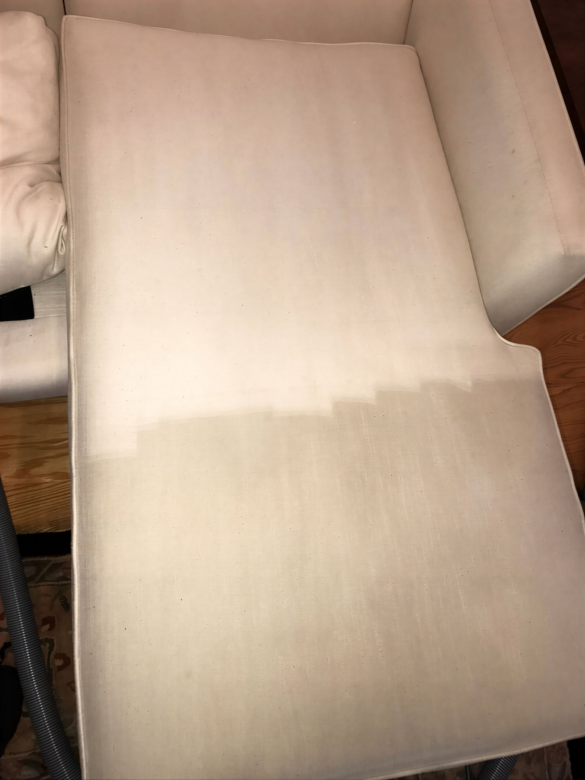 Upholstered chair cushion, light color, appears cleaned on the upper half, with a lighter color compared to the dirtier bottom half.