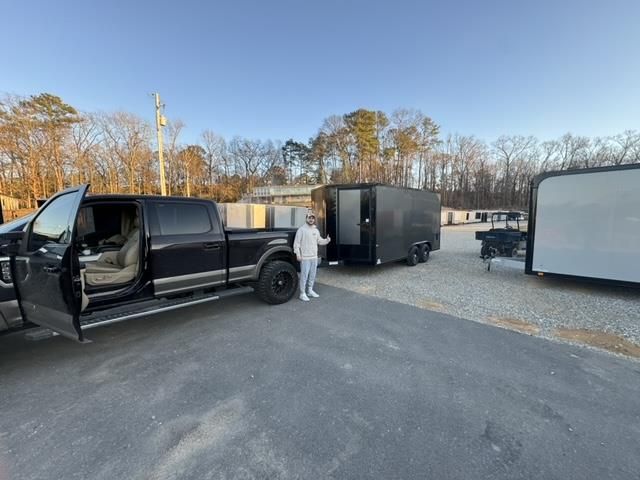 A man is standing in front of a truck and trailer.