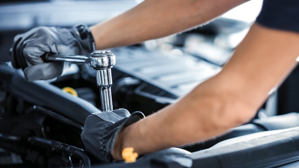 A Mechanic Is Working on A Car Engine with A Wrench — CJ's Holden Spares & Repairs in Queanbeyan West, NSW