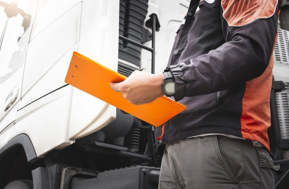 A Man is Holding an Orange Clipboard in Front of a Truck — CJ's Holden Spares & Repairs in Queanbeyan West, NSW