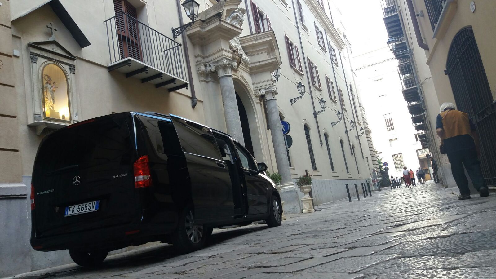 Un furgone nero è parcheggiato su una strada acciottolata di fronte a un edificio