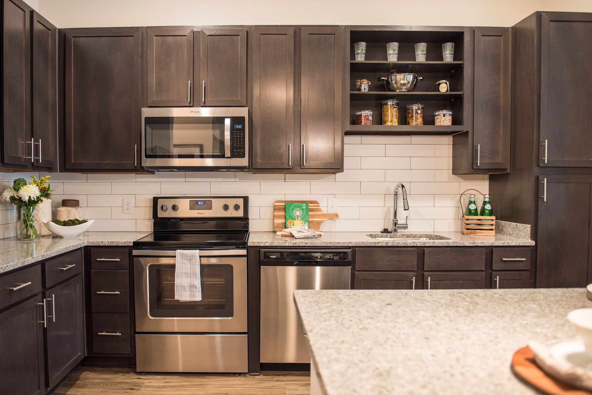 Dark wood kitchen with stainless steel appliances, granite countertops, and open shelves.