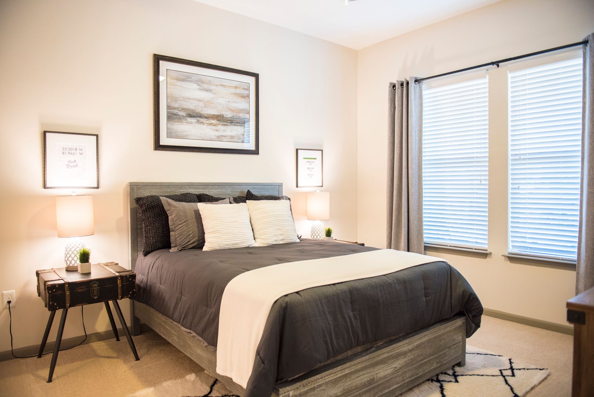 Bedroom with a gray bed, white and gray decor, and two bedside lamps.