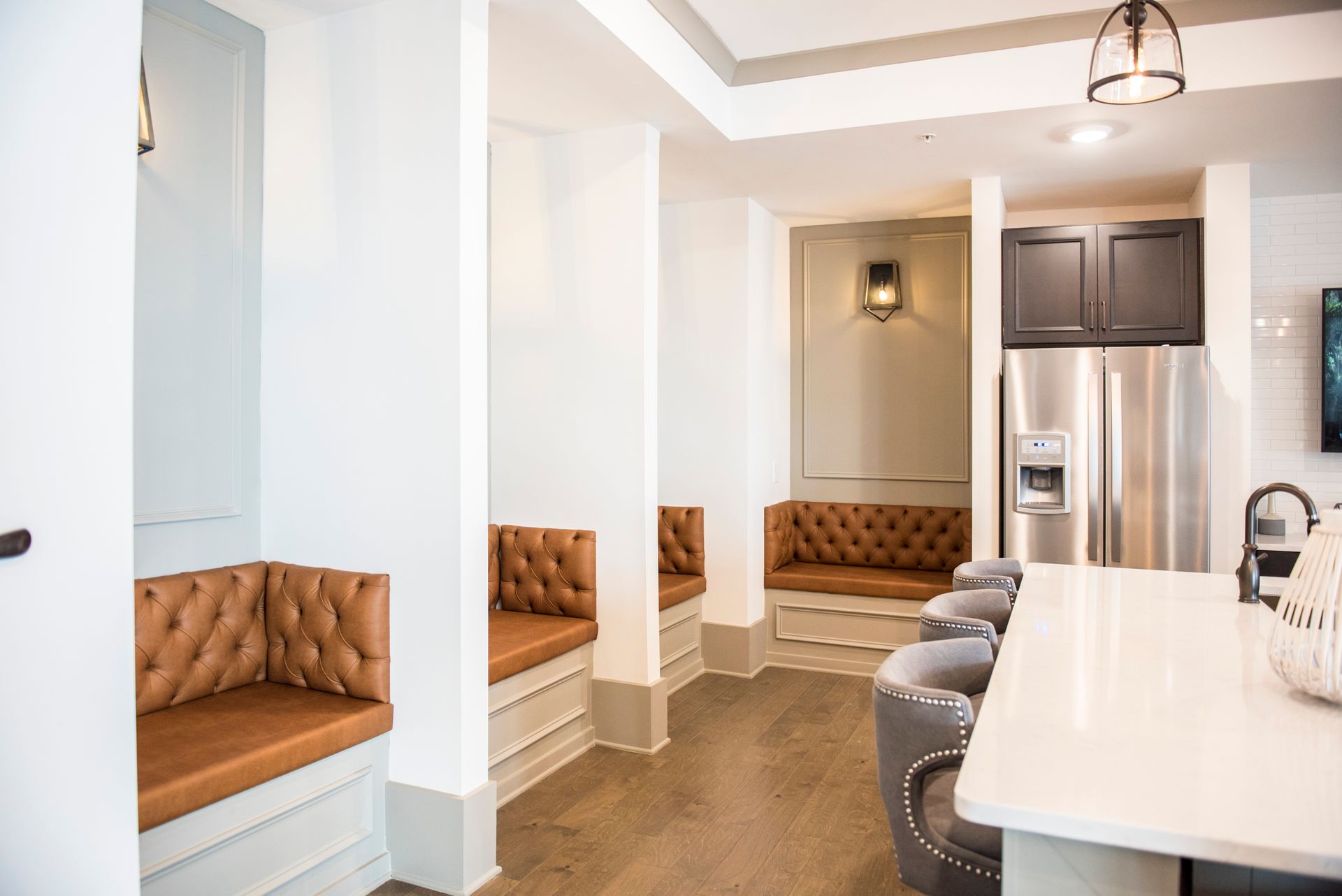 Cozy seating alcoves with brown leather cushions in a bright kitchen with stainless steel appliances.