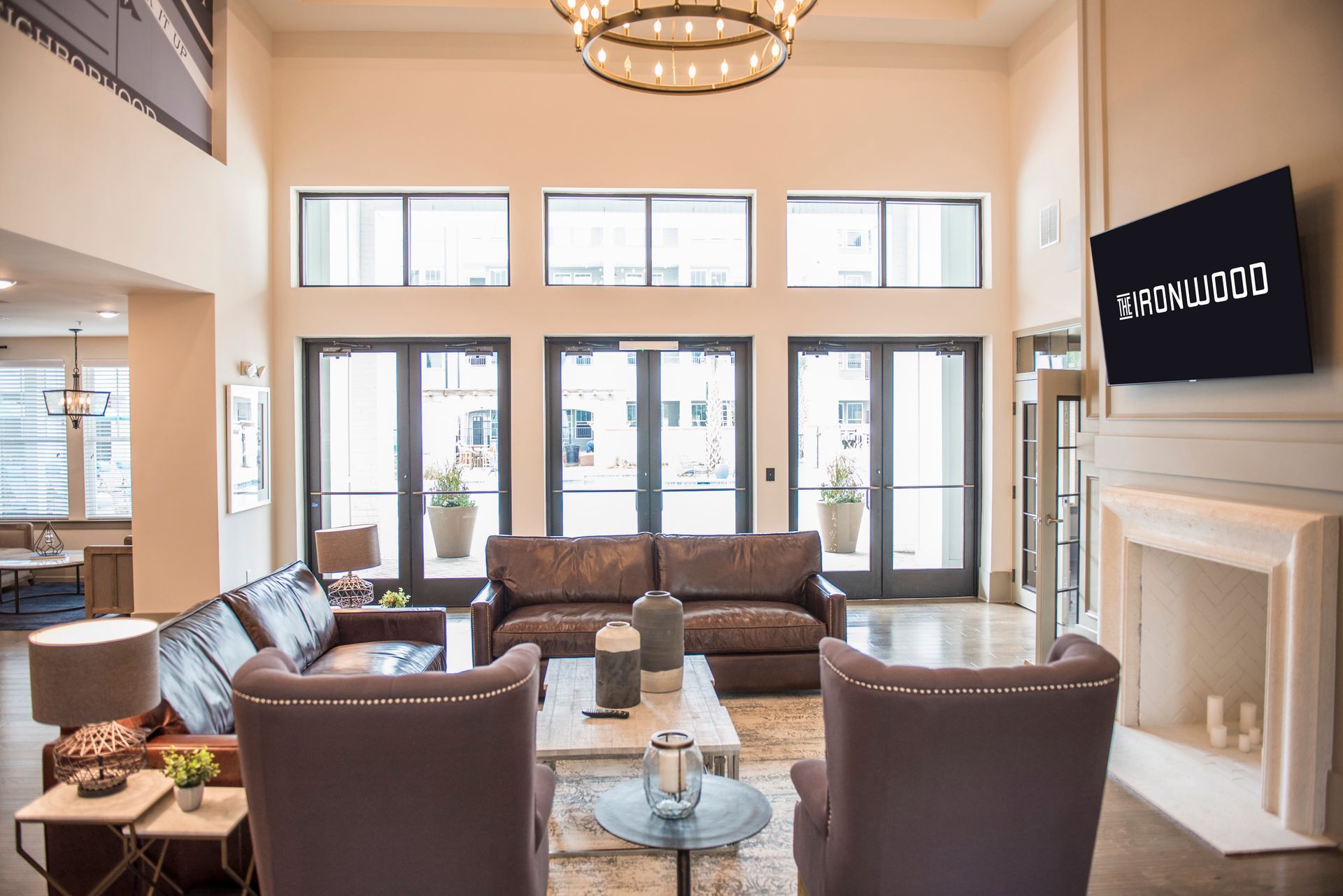 Lobby with seating, fireplace, and television. Large windows and doors lead to the outside.