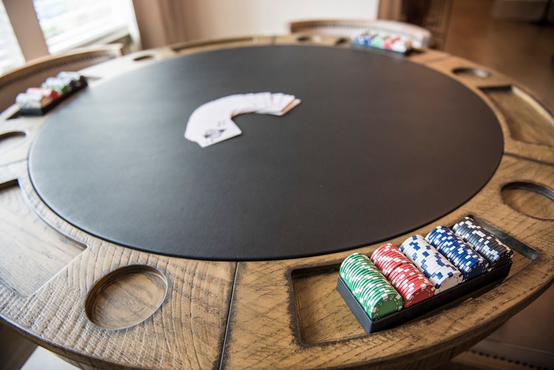 Poker table with cards and chips in a well-lit room.