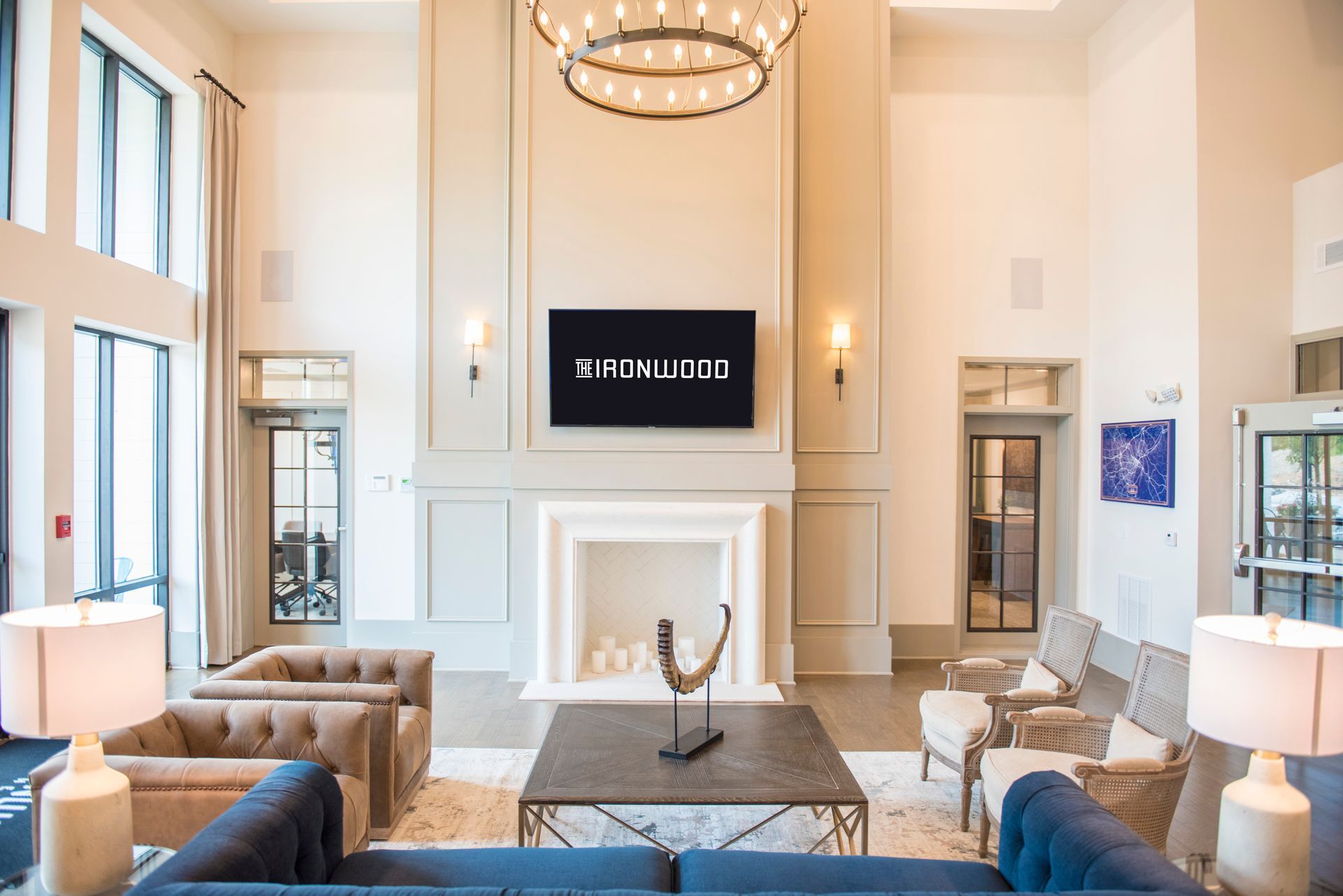 Lobby with seating, fireplace, and TV. Neutral colors, modern design. The Fox Wood logo is displayed on the TV.