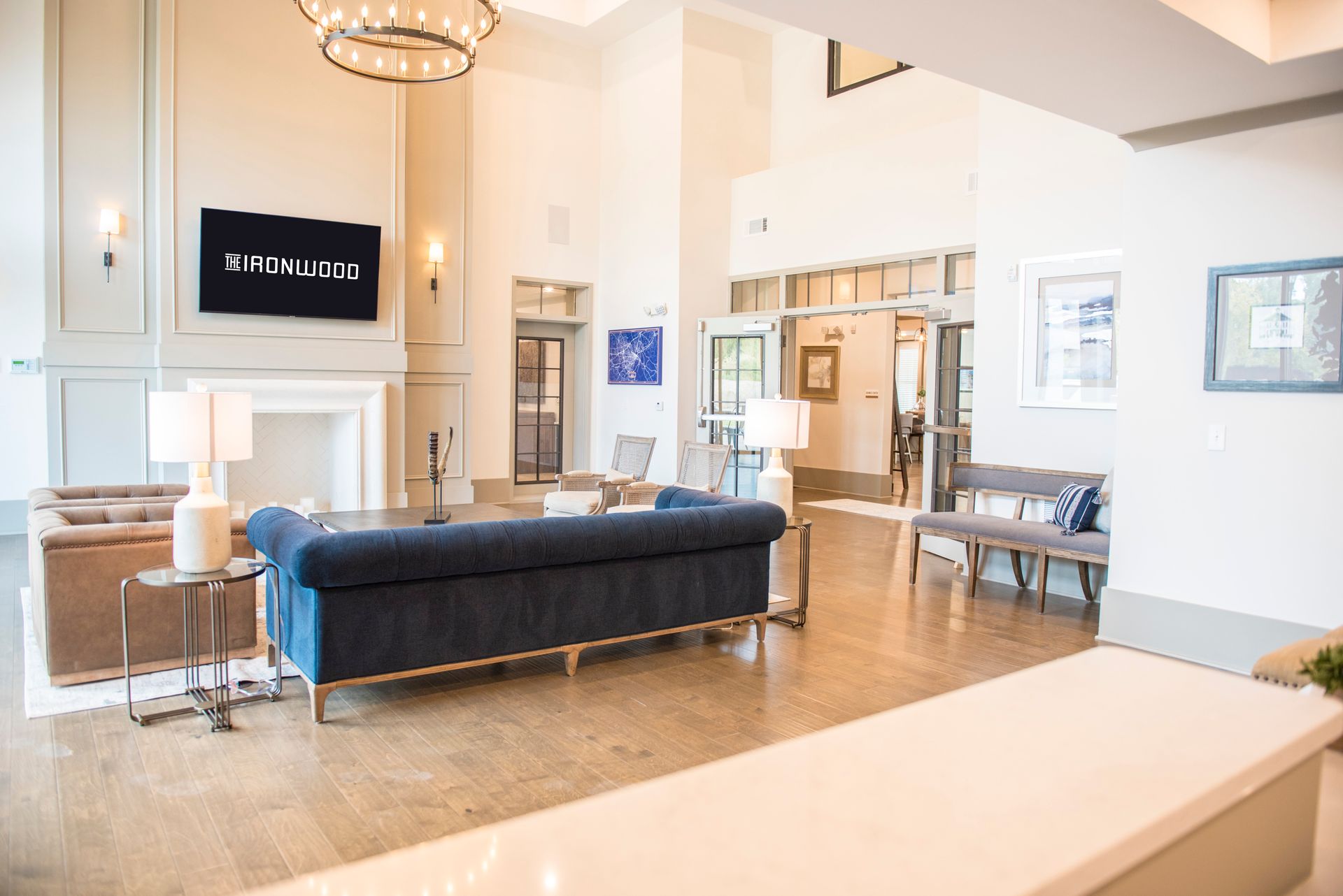 Spacious lobby with blue sofa, fireplace, and reception desk. Light wood floors, neutral tones, and elegant fixtures.
