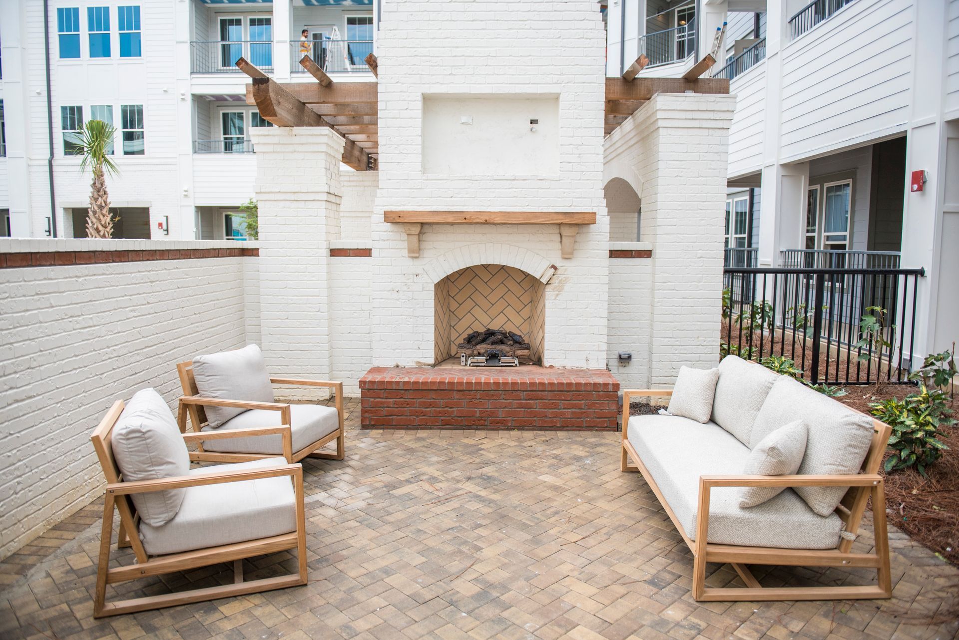 Outdoor seating area with a white brick fireplace and wooden furniture.