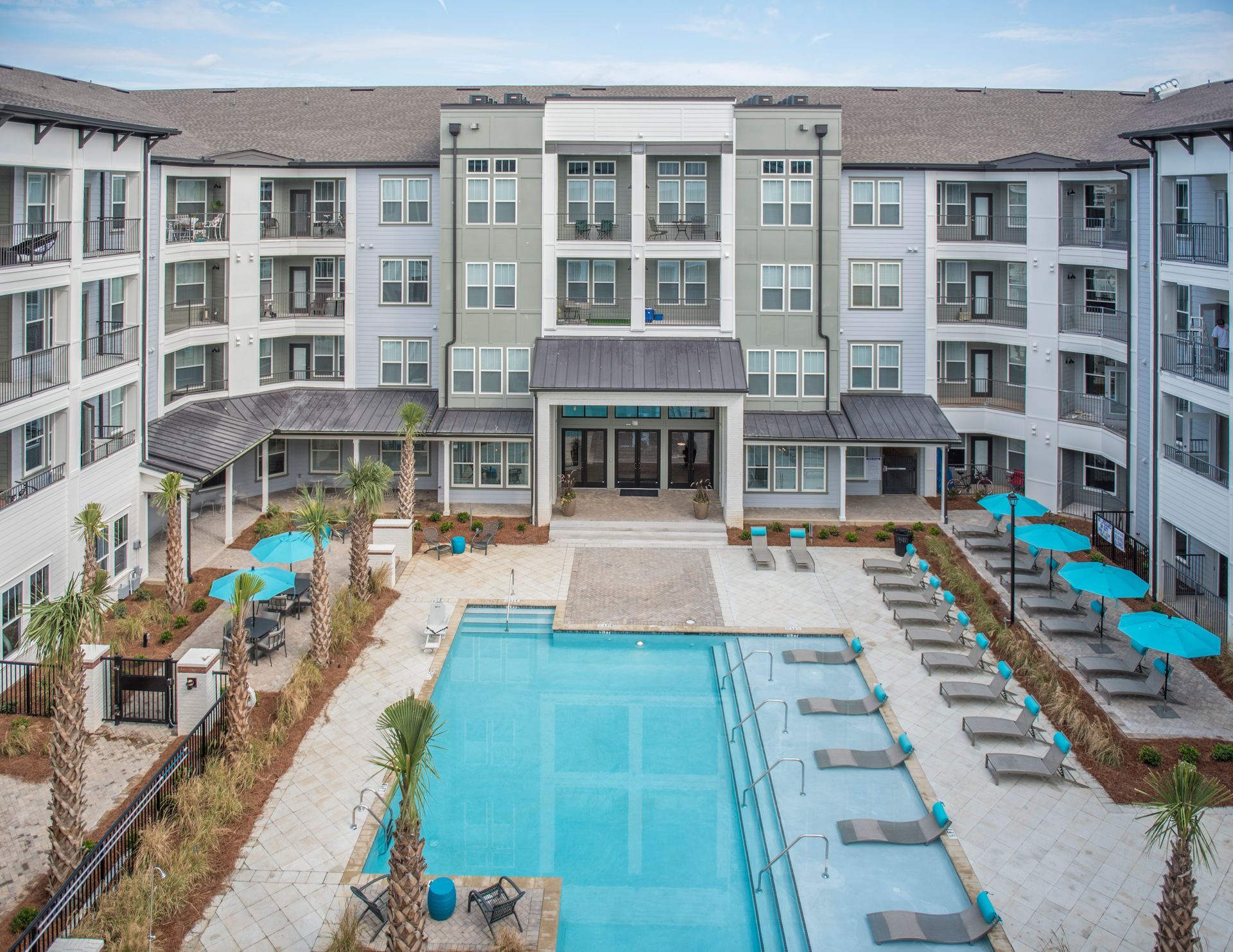 Aerial view of apartment complex with pool and lounge chairs.