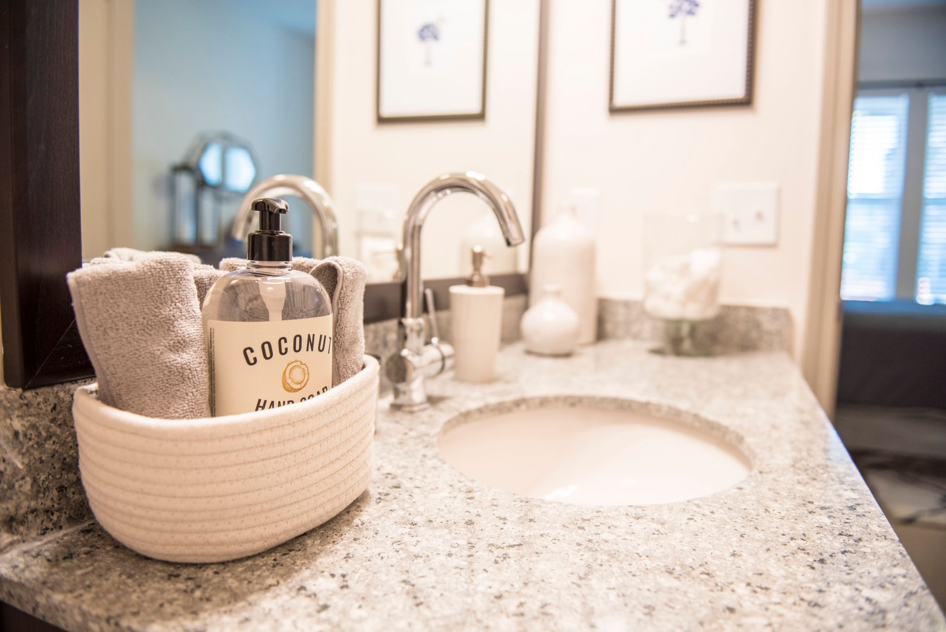 Bathroom sink with towels, soap, and decorations on a granite countertop.
