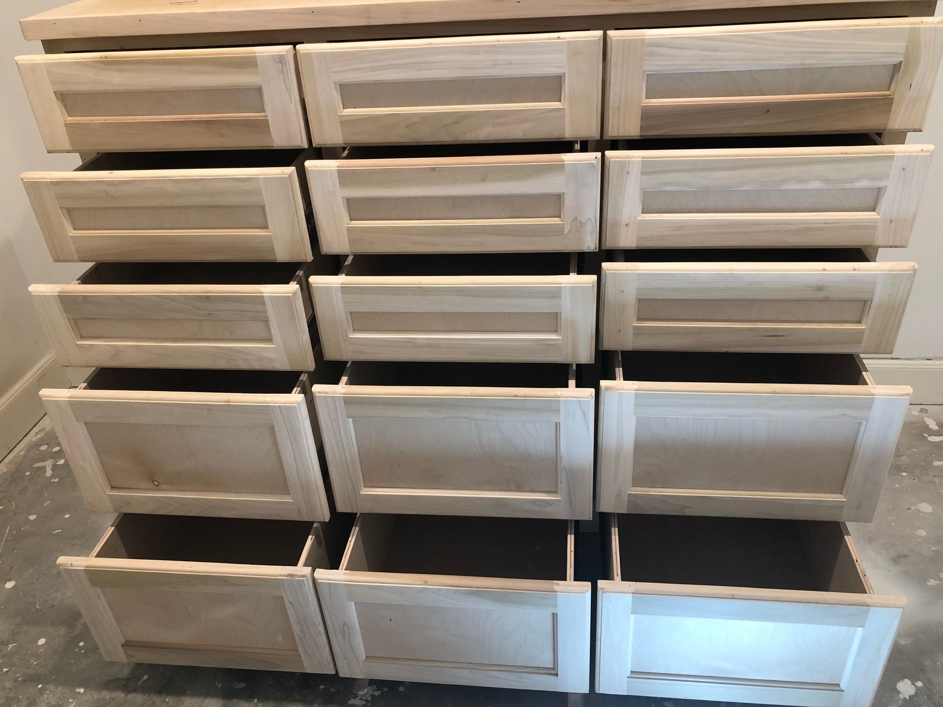 A wooden dresser with three columns of drawers, all shown in various stages of being opened.
