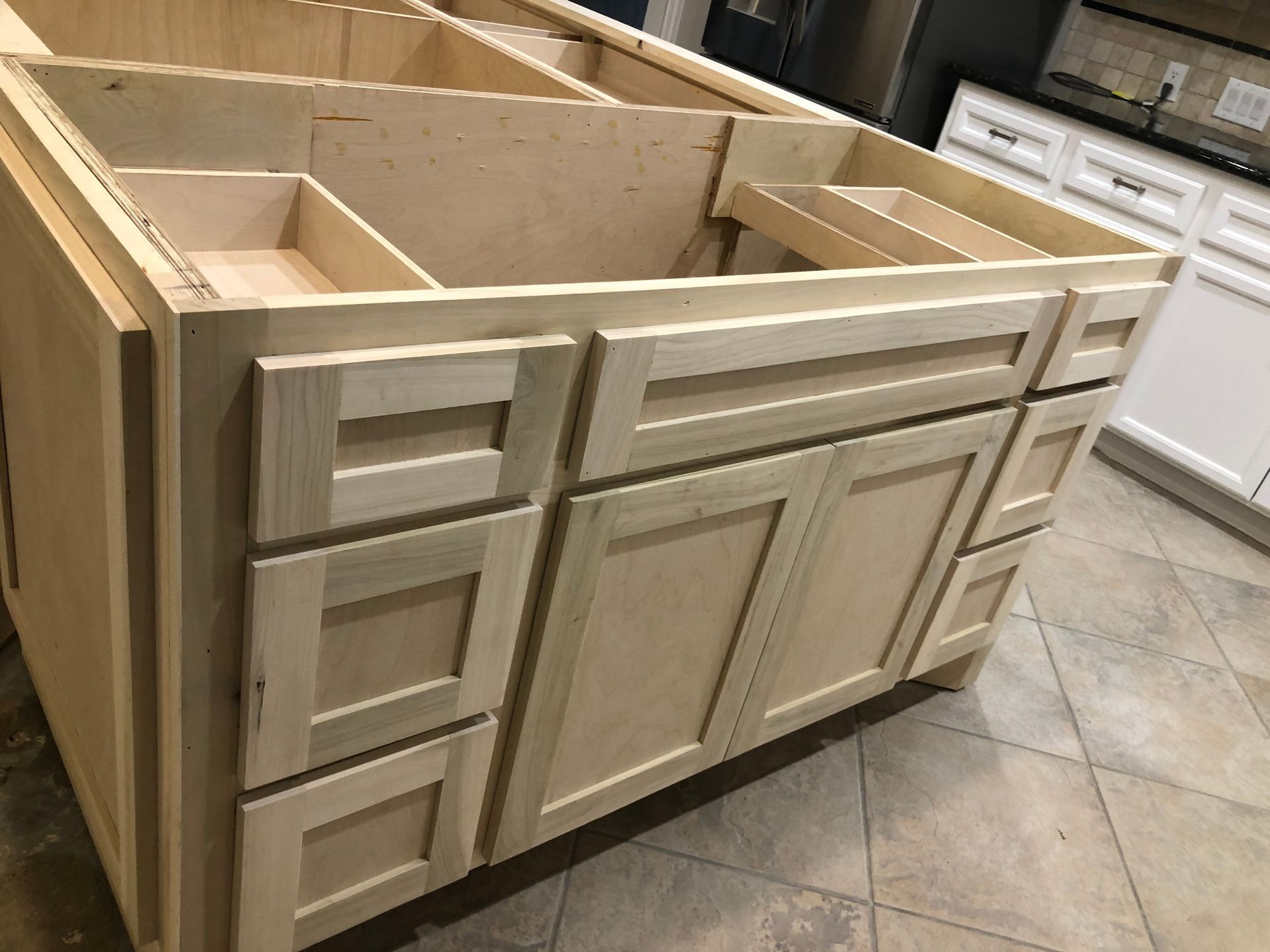Unfinished wooden kitchen island cabinetry featuring drawers and double cabinet doors in a home kitchen.